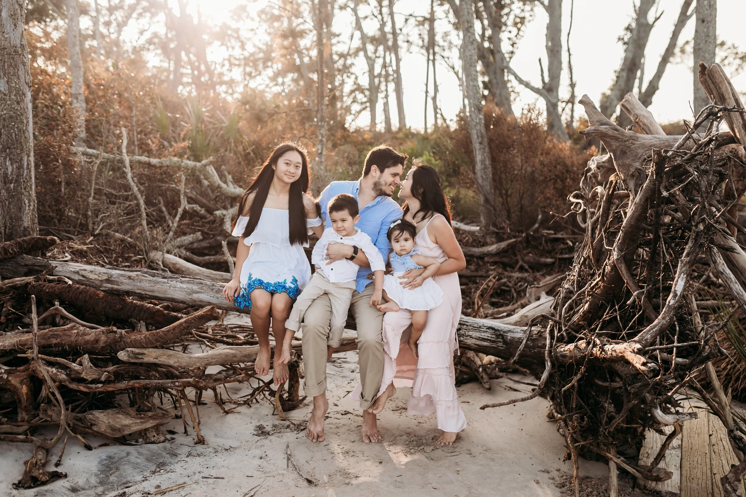 Family posing together on driftwood along the shoreline at Big Talbot Island Boneyard Beach near Jacksonville Florida