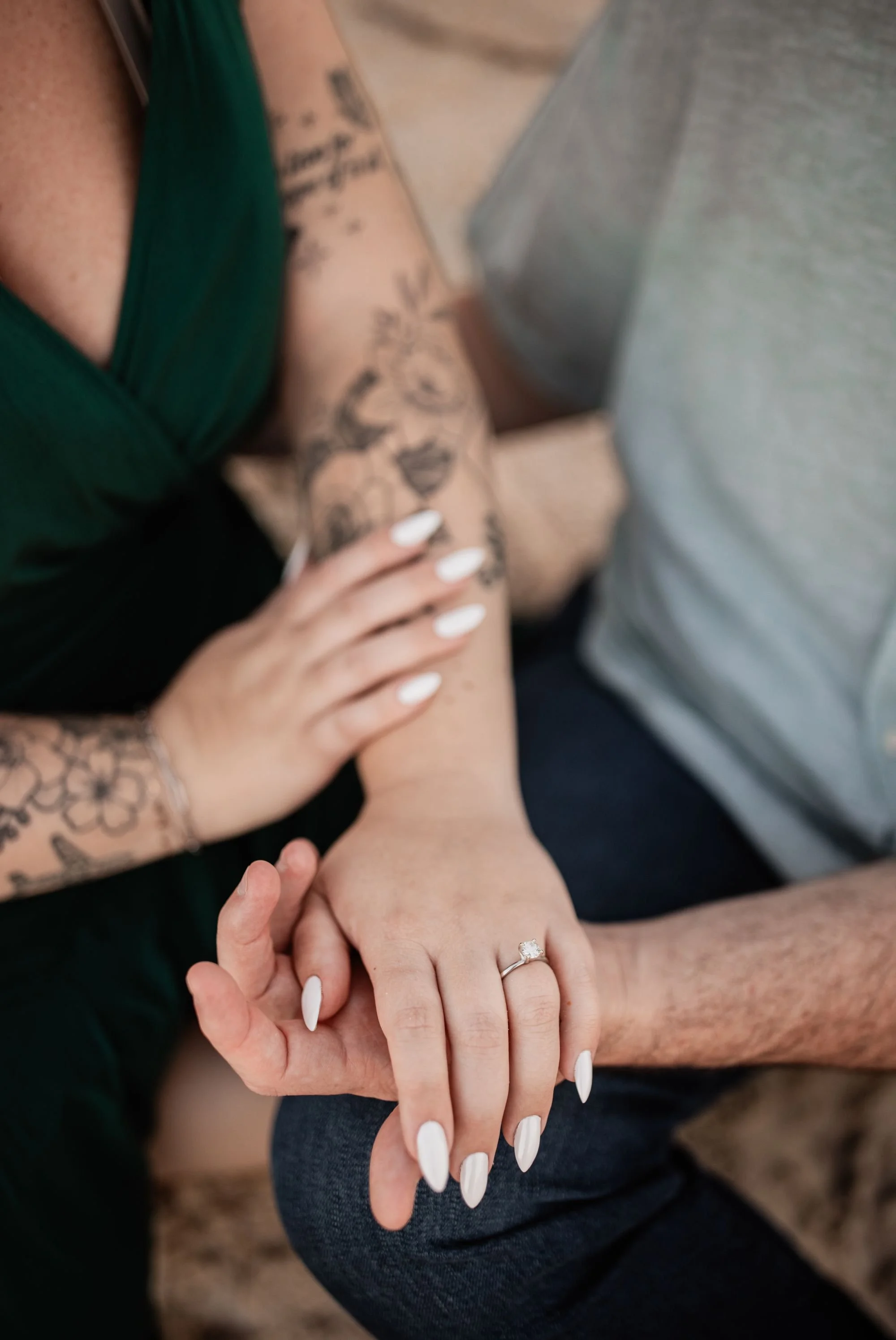 Close-up of the bride-to-be's engagement ring as the couple sits together during their beach session.