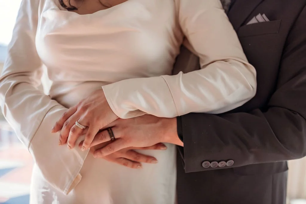 Close-up of Stephanie and Gary holding each other with their wedding rings visible