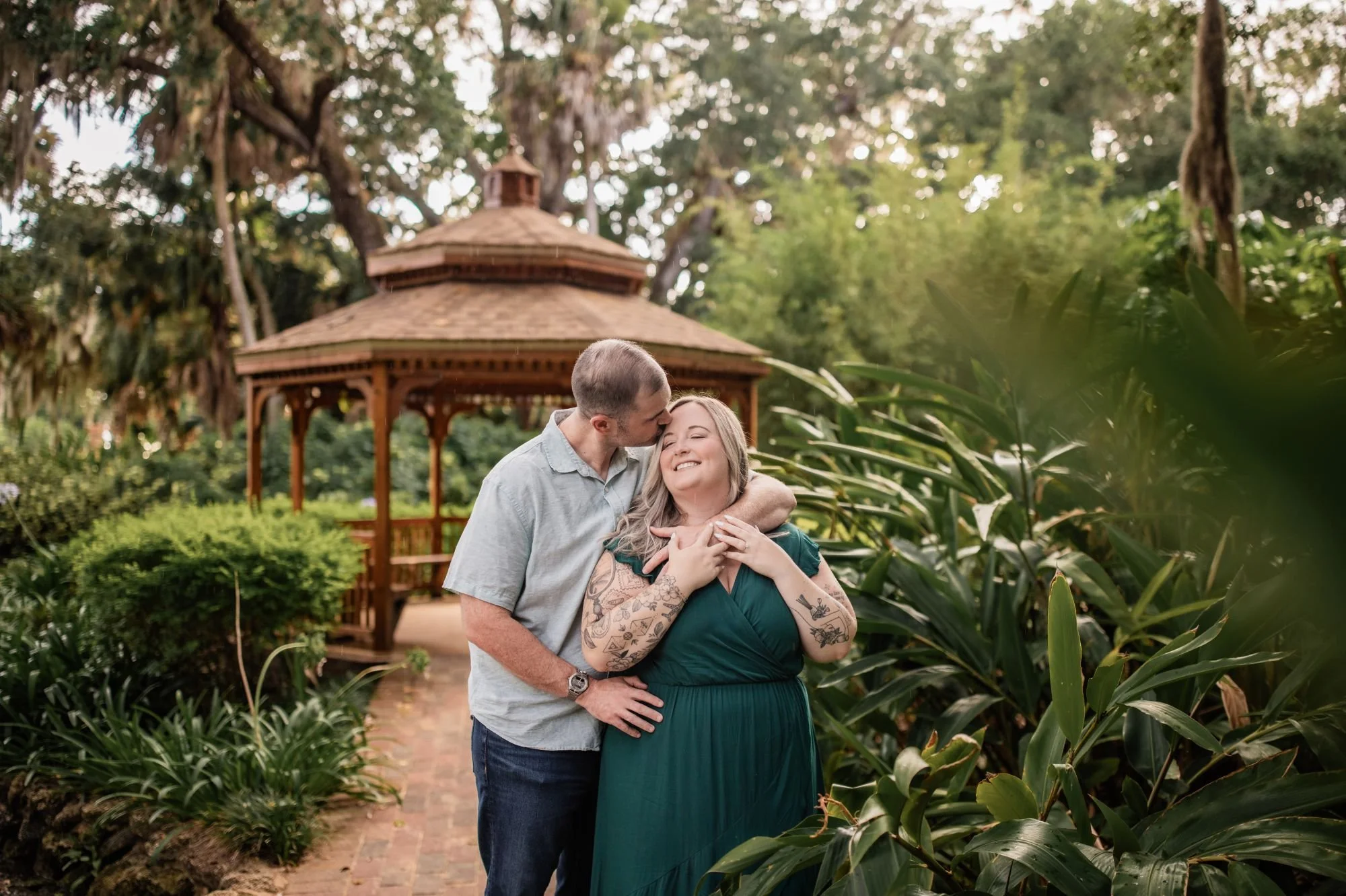 Couple embracing in the lush gardens near the wooden gazebo at Washington Oaks State Park
