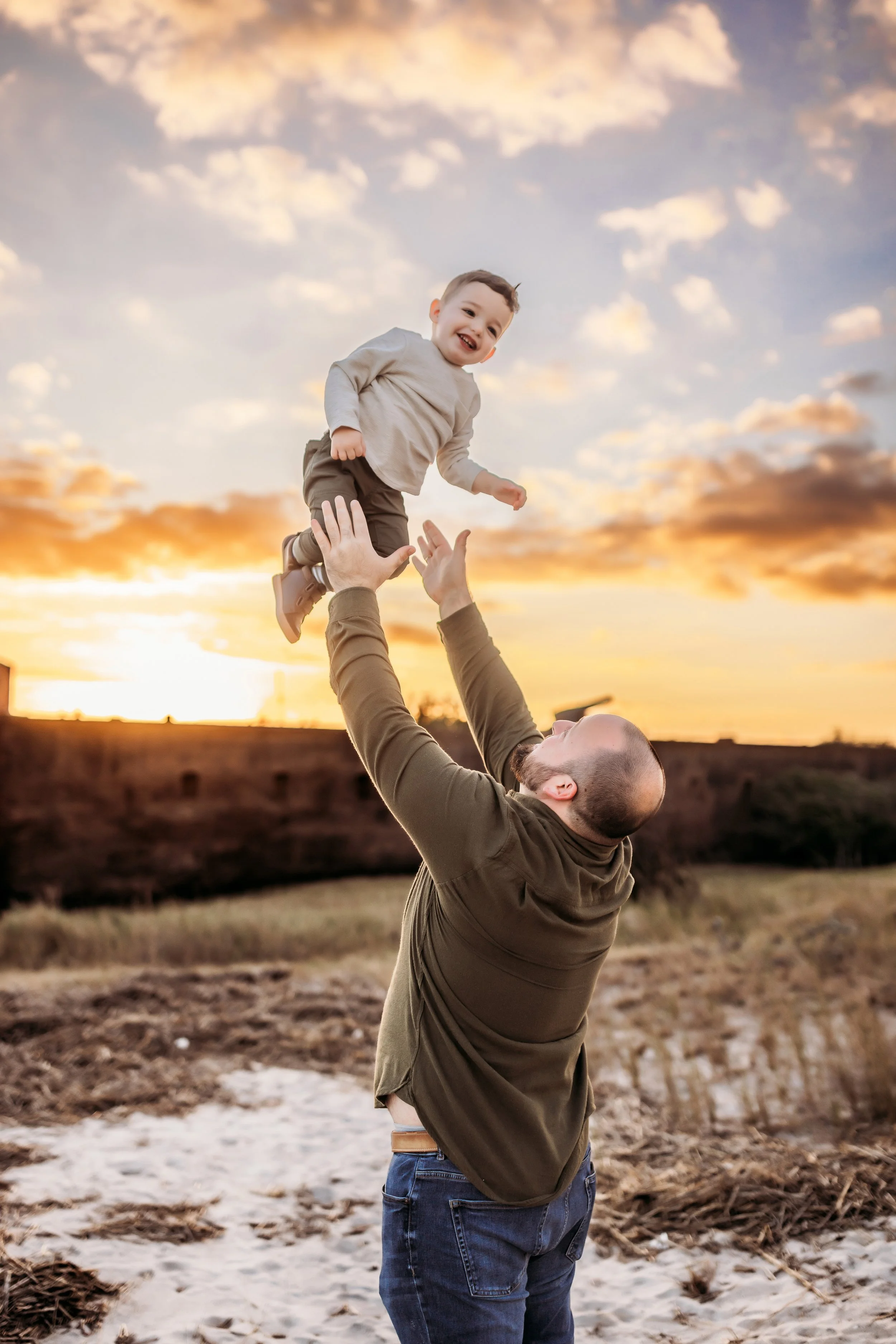 Parent lifting their child into the air during golden hour at Fort Clinch in Fernandina Beach on Amelia Island Florida