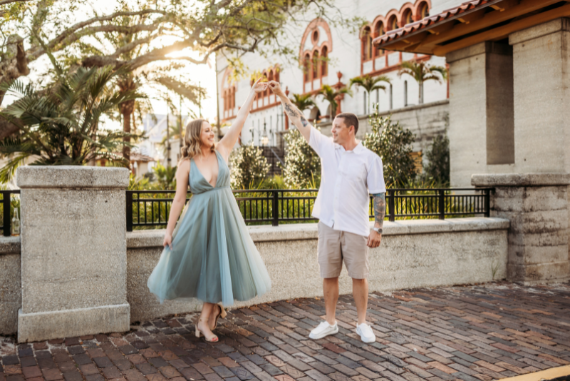 Couple dancing on a St Augustine brick street in a sage tulle dress and neutral outfit