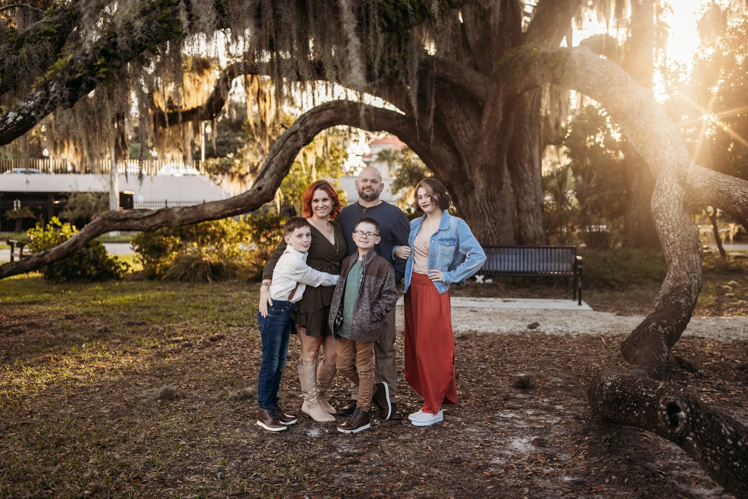 Playful family moment in Riverside Park in Jacksonville Florida with parents hugging their kids under oak trees