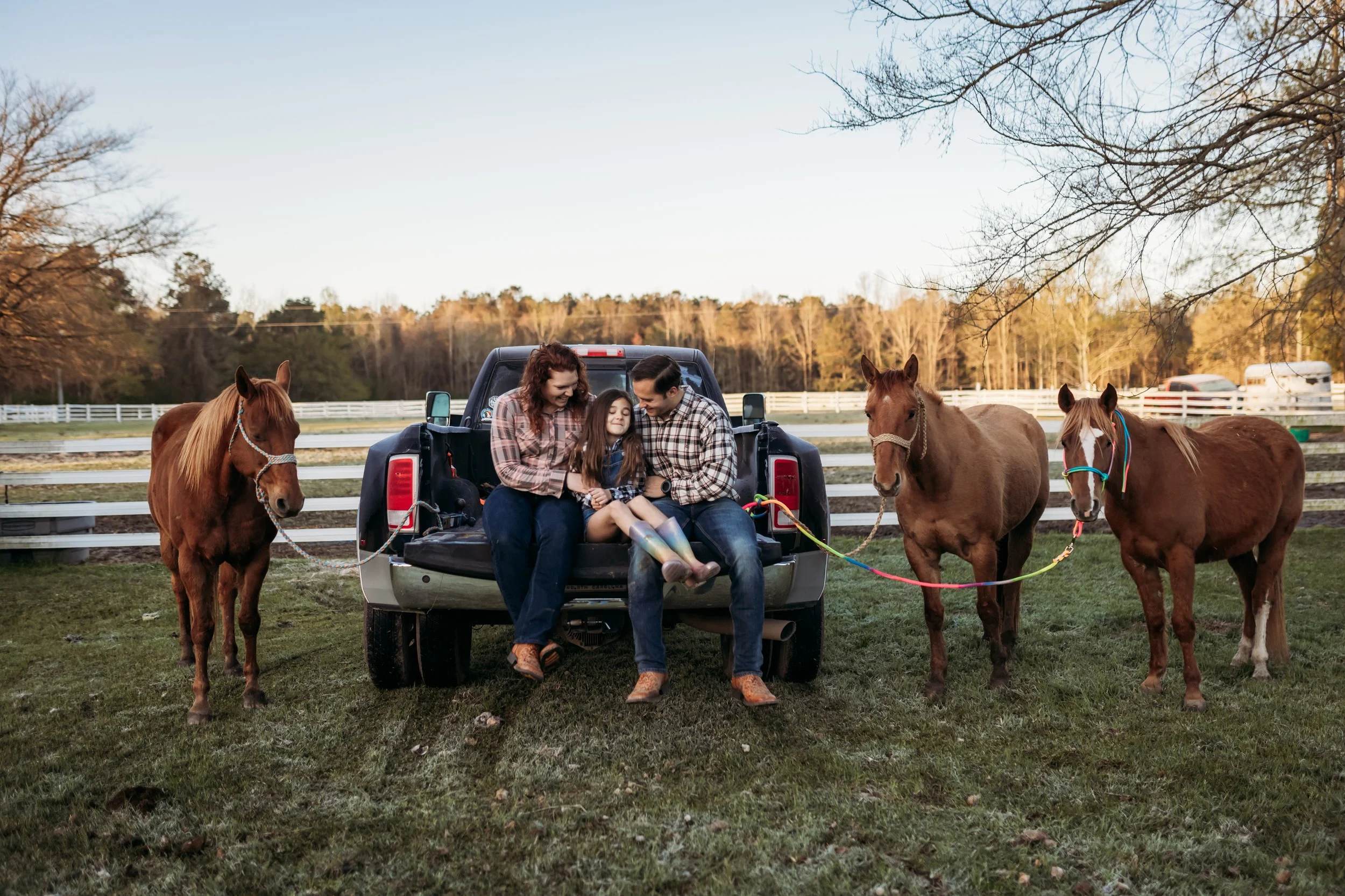 Family sitting in the back of a truck surrounded by horses during a countryside session in Callahan near Jacksonville Florida