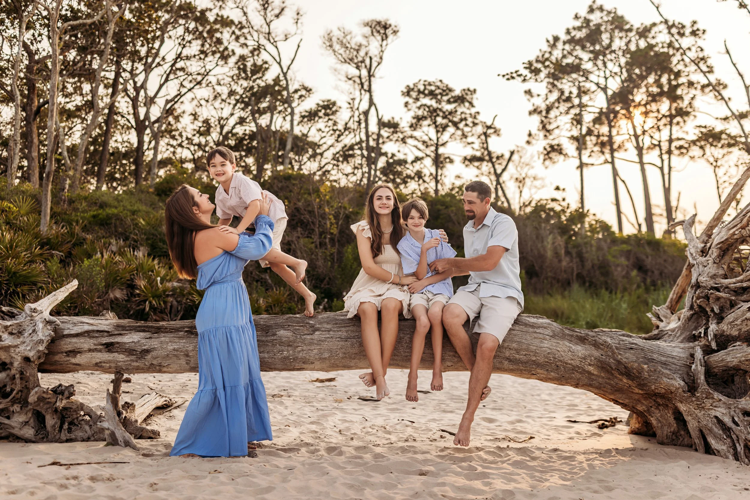Family playing together on driftwood at Boneyard Beach in Big Talbot Island near Jacksonville Florida during a golden hour session