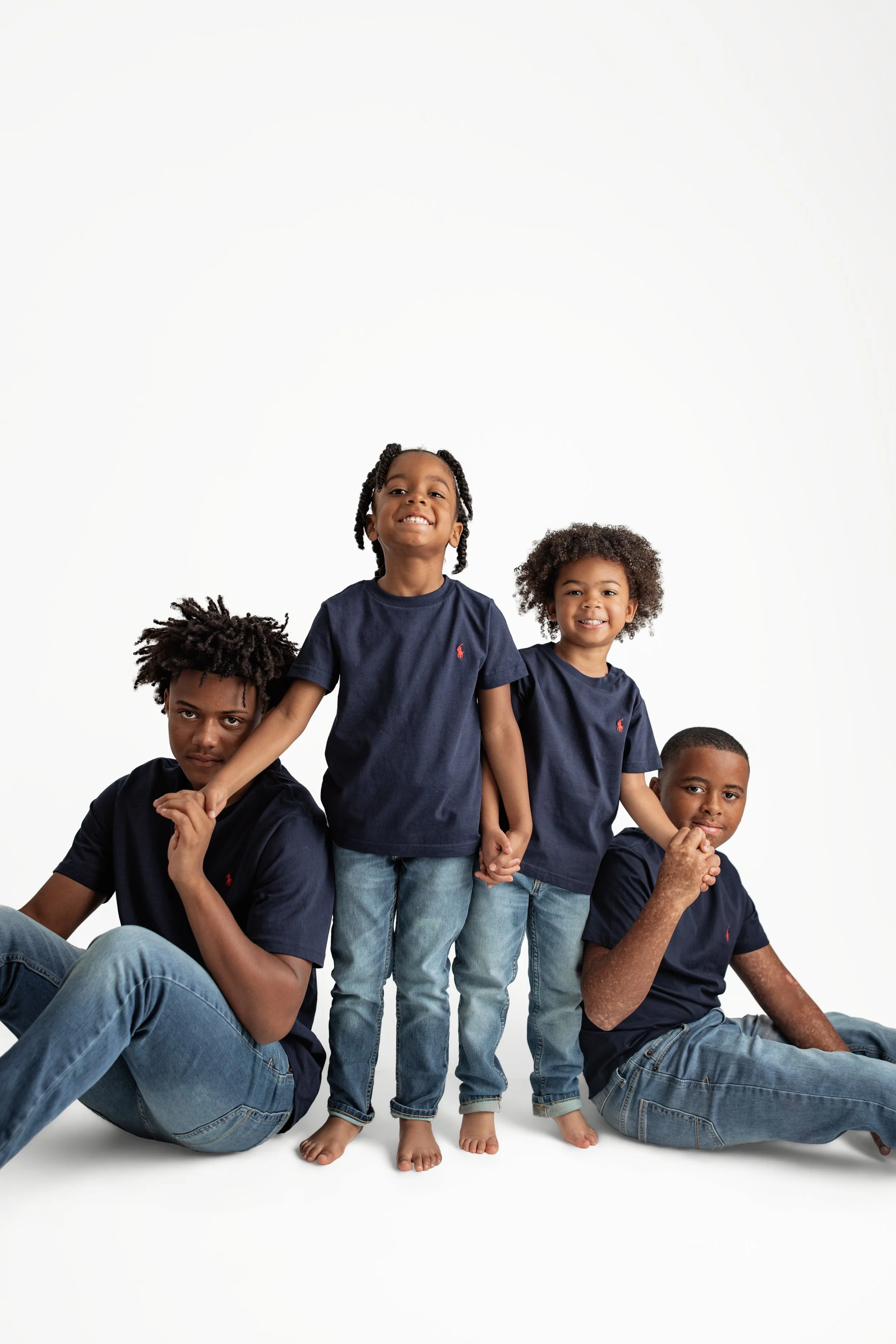 Four kids posing together in a clean studio setting, smiling and showing playful personalities during a Jacksonville family session