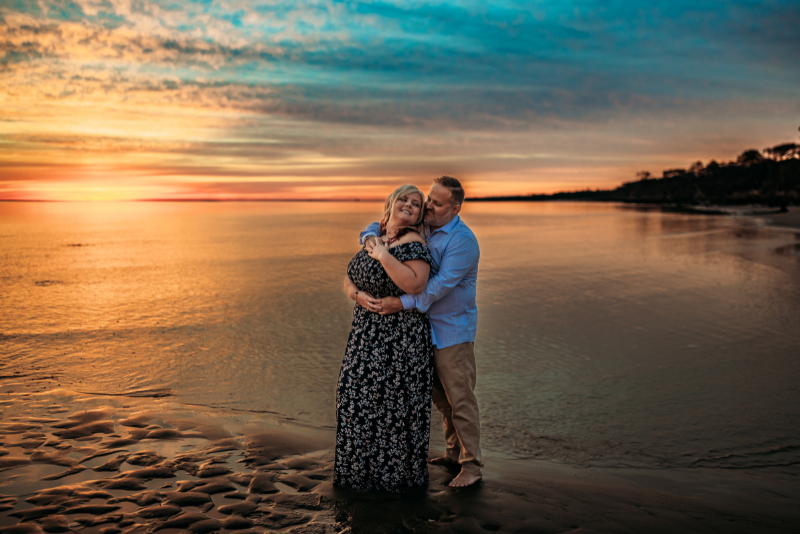 Expecting couple at sunset in a black floral maxi dress and pale blue shirt