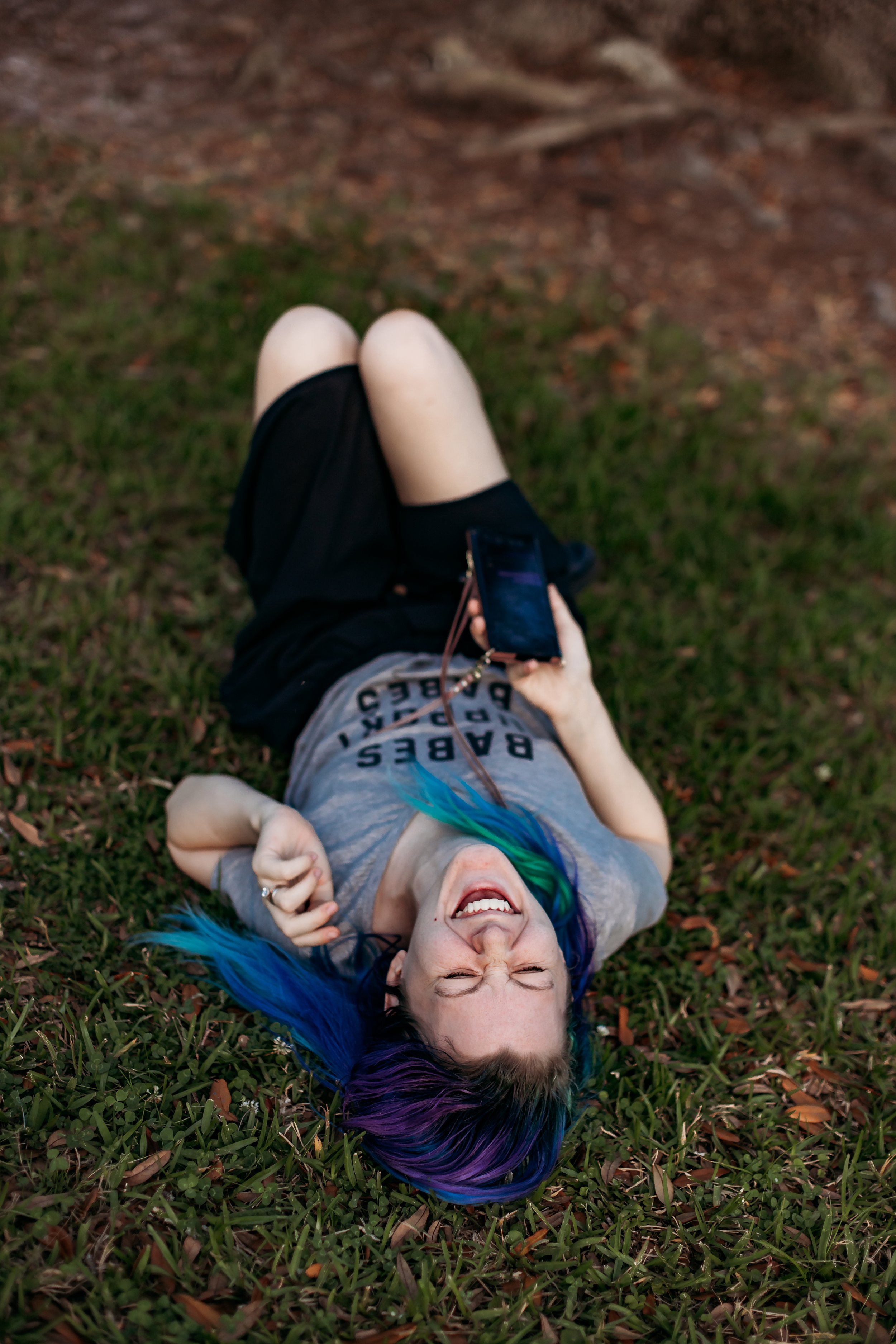 Jacksonville Florida wedding and elopement photographer Tiffany Joyce laughing while lying on grass during a candid behind the scenes moment