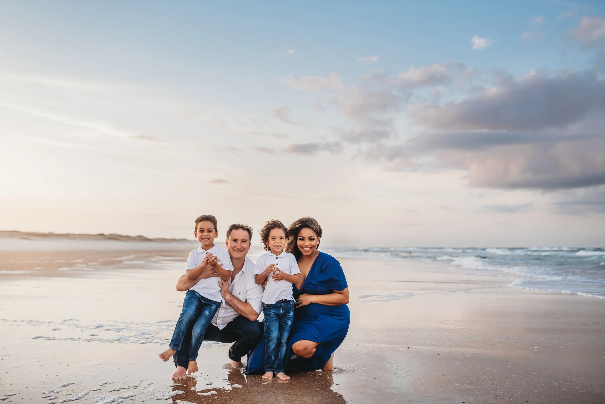 Family sitting together on the beach at Anastasia State Park in St. Augustine Florida during a sunset session