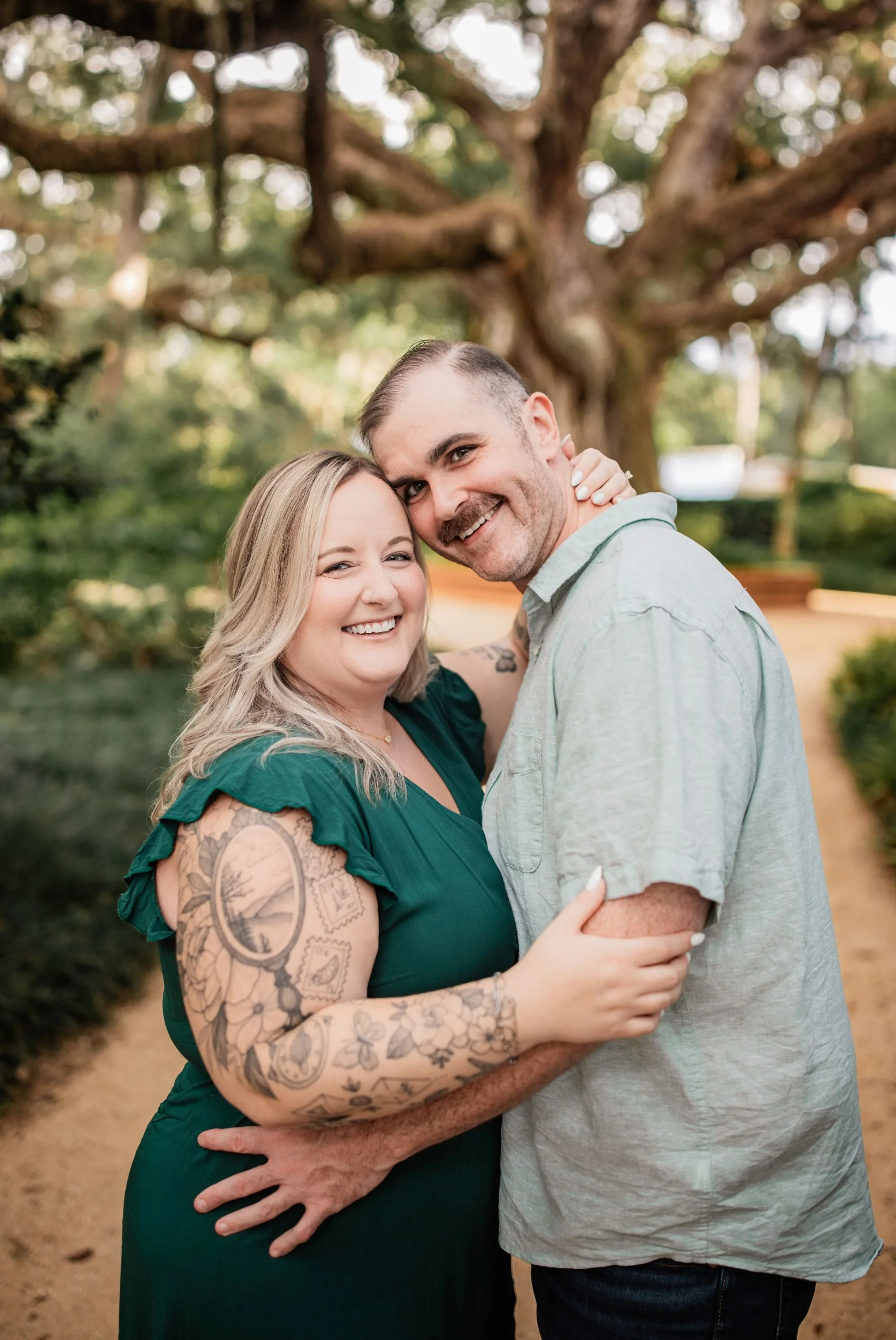 Smiling engaged couple posing together in the gardens at Washington Oaks State Park.