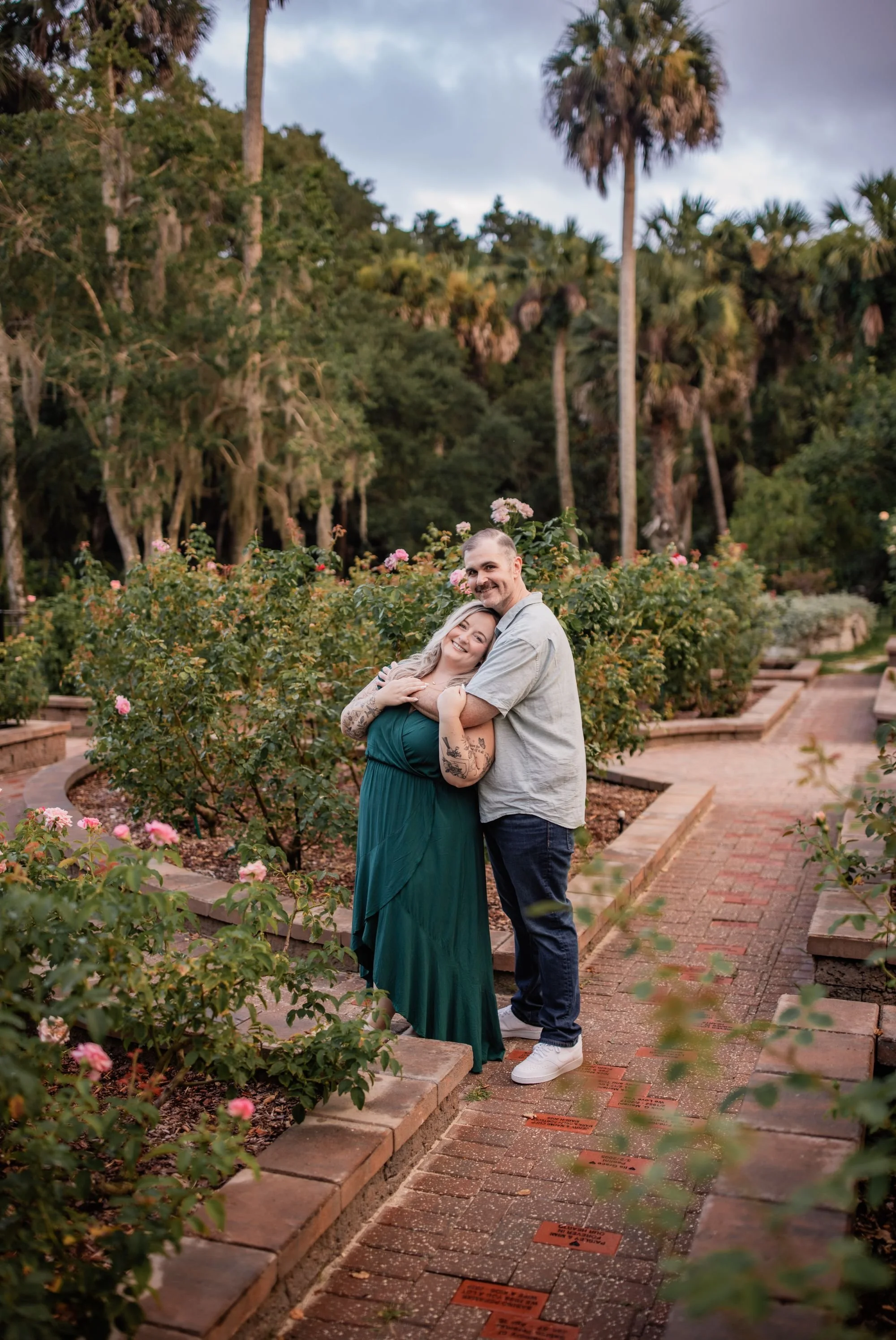Couple embracing among blooming roses and palm trees at Washington Oaks Gardens State Park.