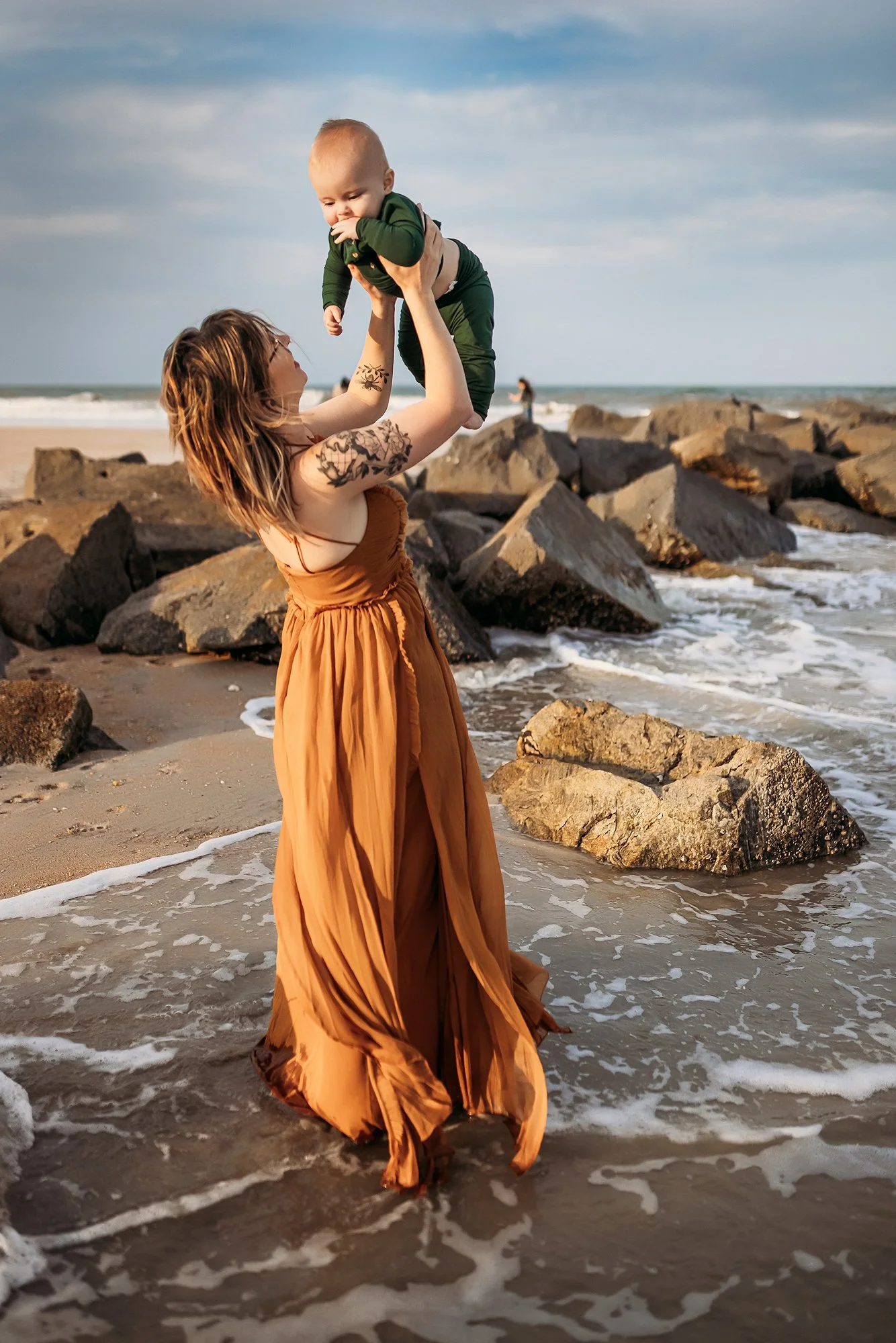 Mother holding her baby near the ocean waves at Vilano Beach in St. Augustine Florida during a golden hour session