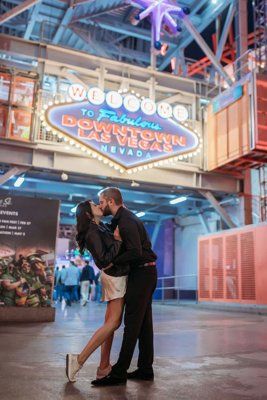Stephanie and Gary stand together beneath colorful Fremont Street signs