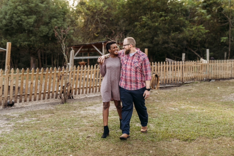 Couple walking beside a wooden fence in coordinated mauve, red plaid, and navy outfits