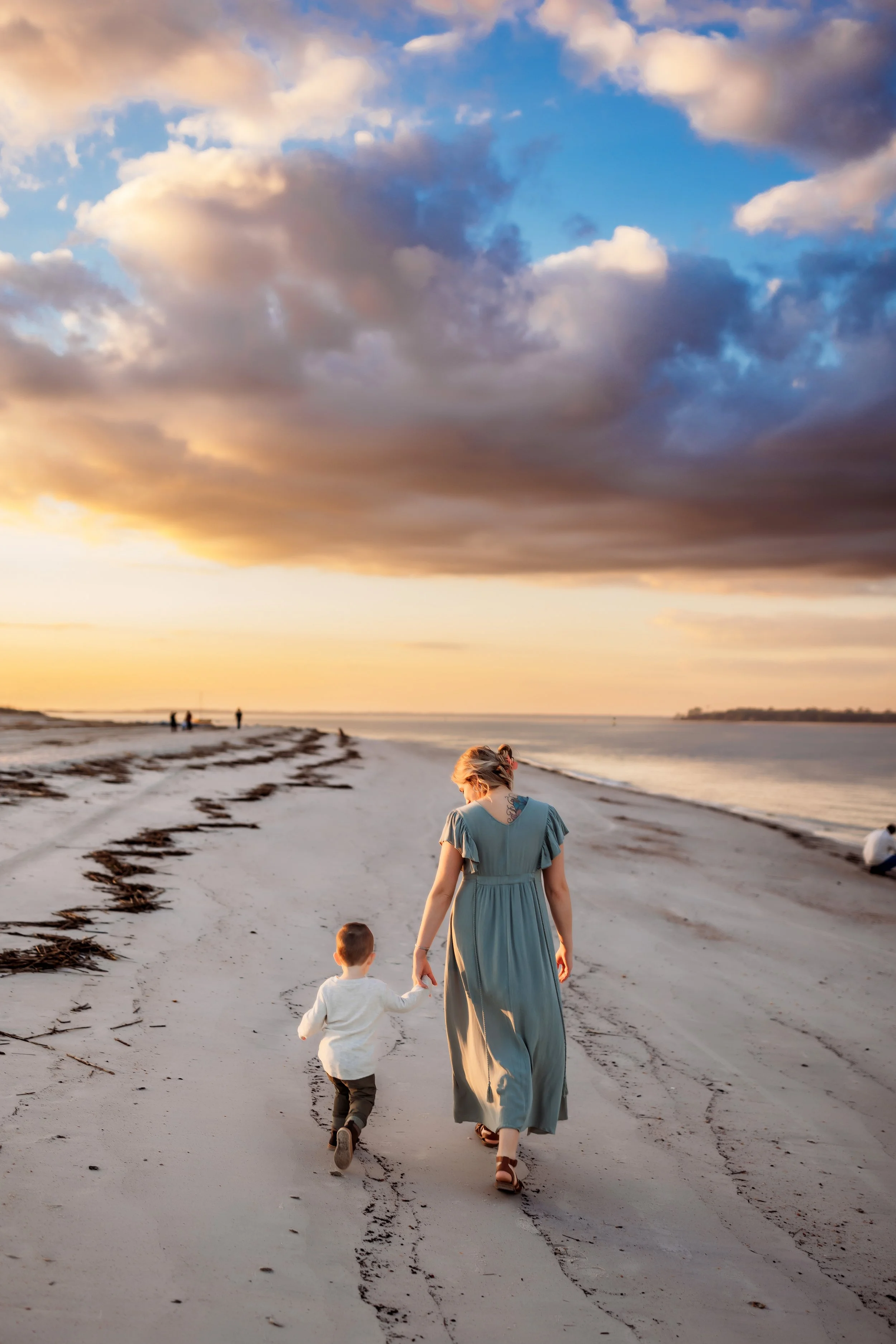 Candid family moment at Fort Clinch State Park in Florida with mom holding child’s hand during sunset beach session