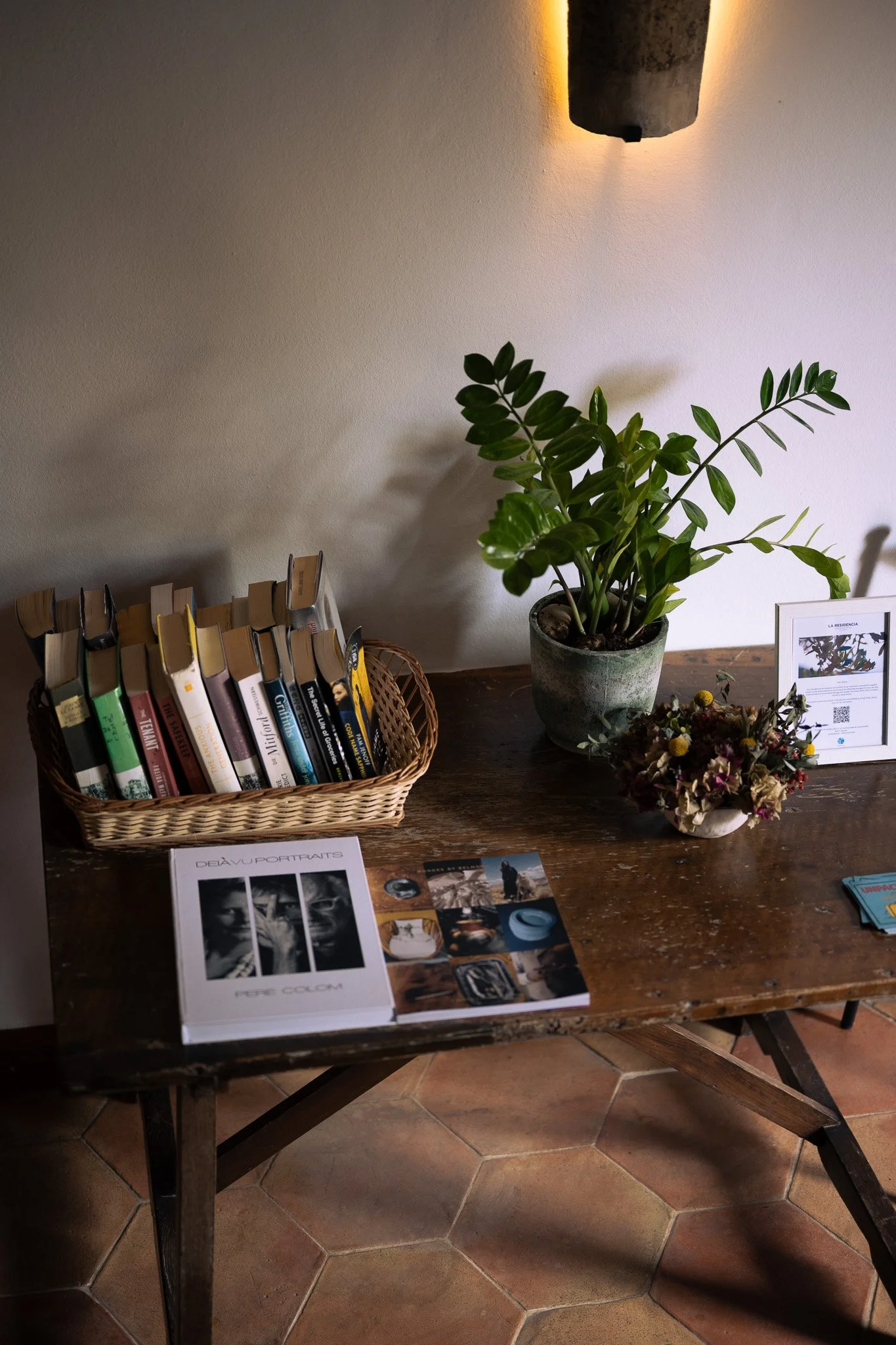 Books, plants and dried flowers arranged on a rustic wooden table inside La Residencia in Mallorca.