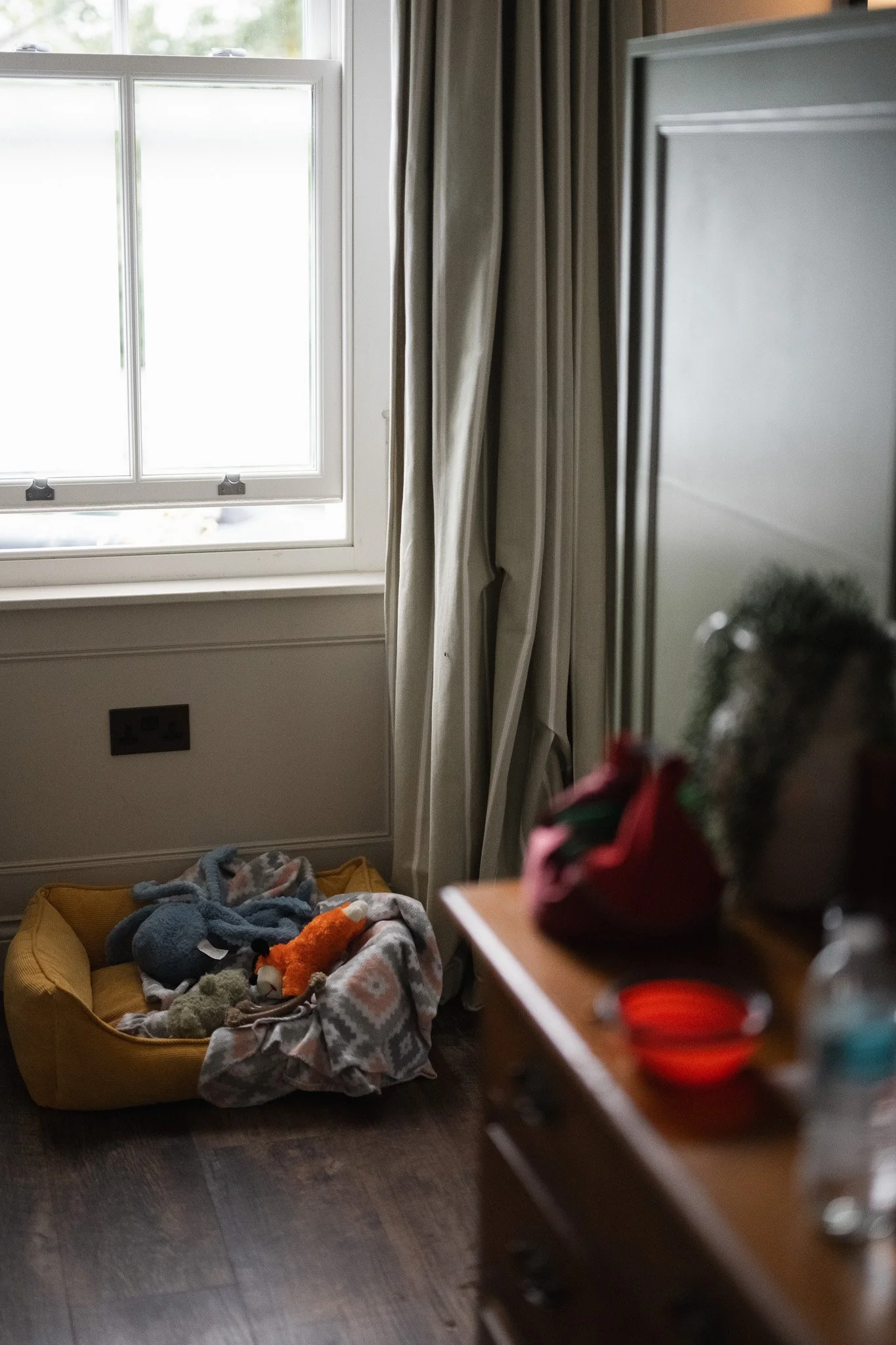 Dog bed, toys and water bowl arranged beside the window in a room at The Penn.