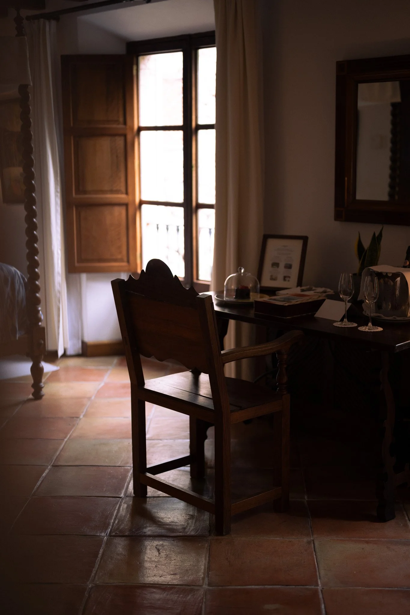 Wooden chair and writing table beside a sunlit window in a guest room at La Residencia, Mallorca.