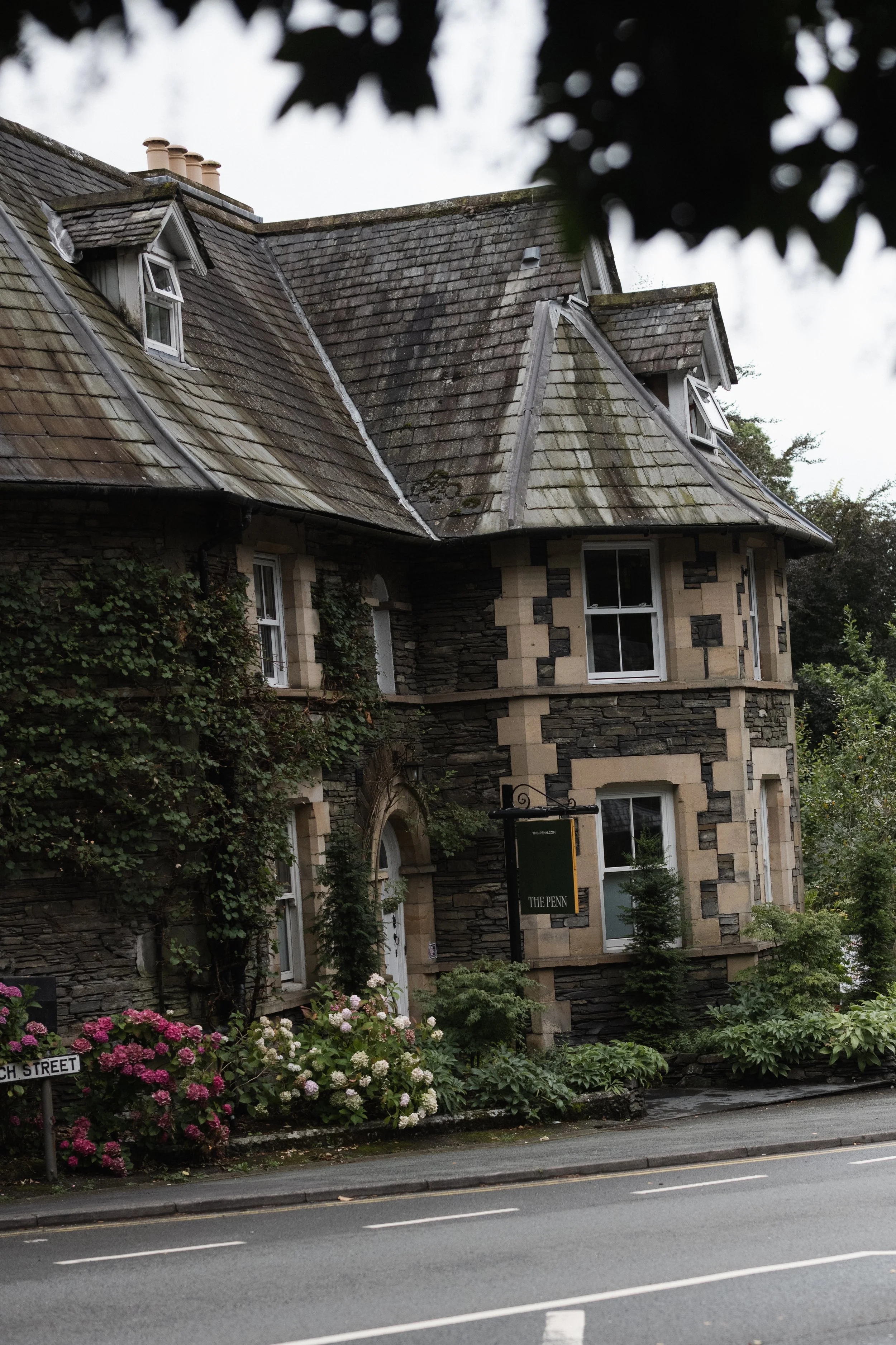 Exterior of The Penn in Windermere on an overcast day, surrounded by trees and greenery.