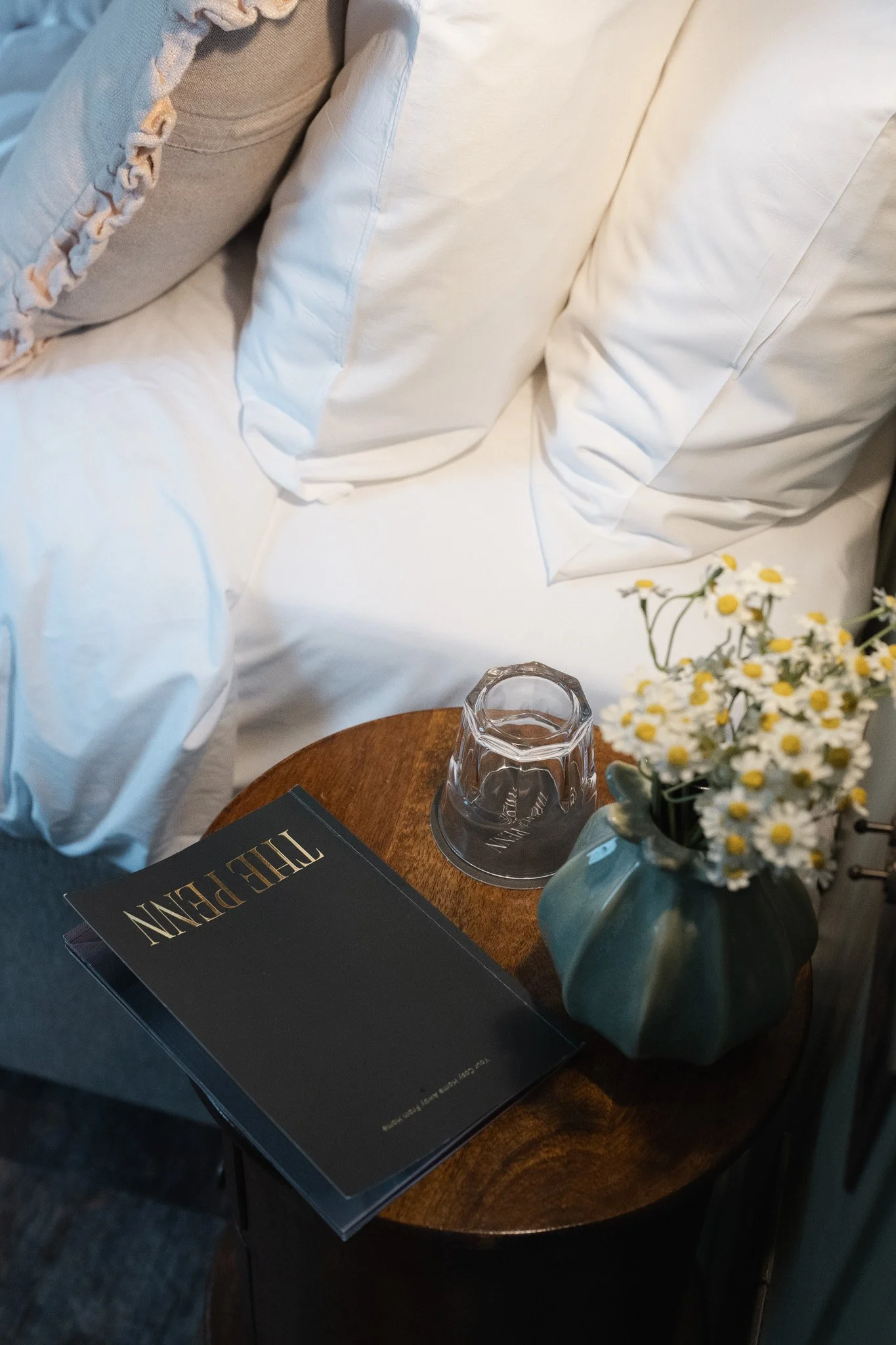The Penn guest book resting on a bedside table beside a lamp and dried flowers.