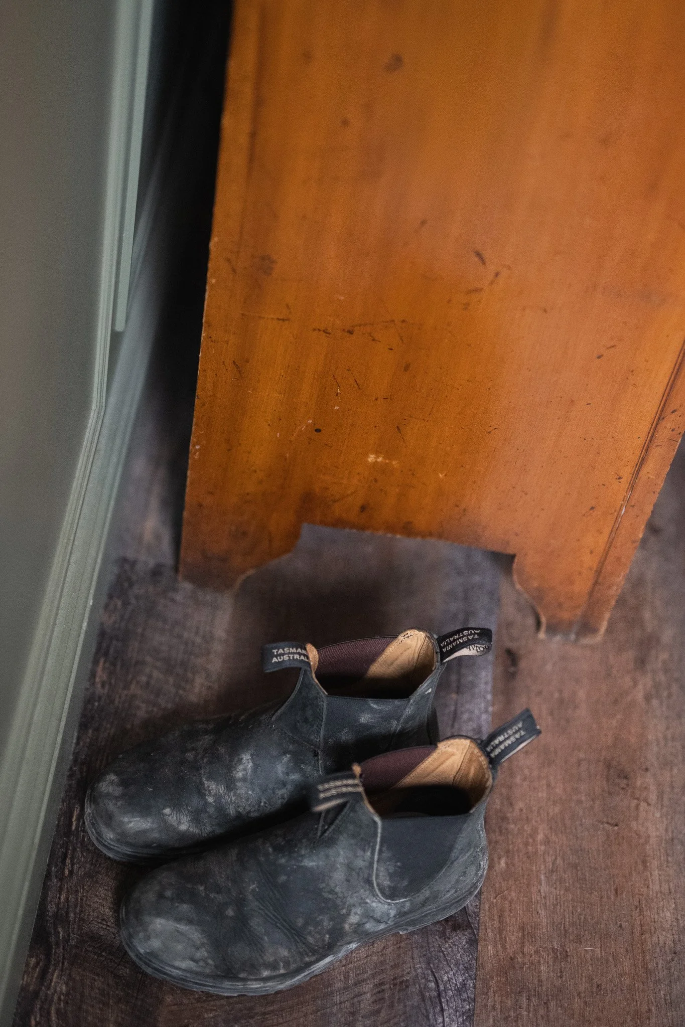Muddy walking boots on the floor beside a chair after a rainy Lake District walk.