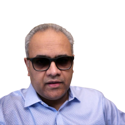 Person wearing sunglasses indoors, dressed in a light blue shirt, seated in a room with patterned pillows in the background talking about money and its effect on our daily lives. isolated on a white background.