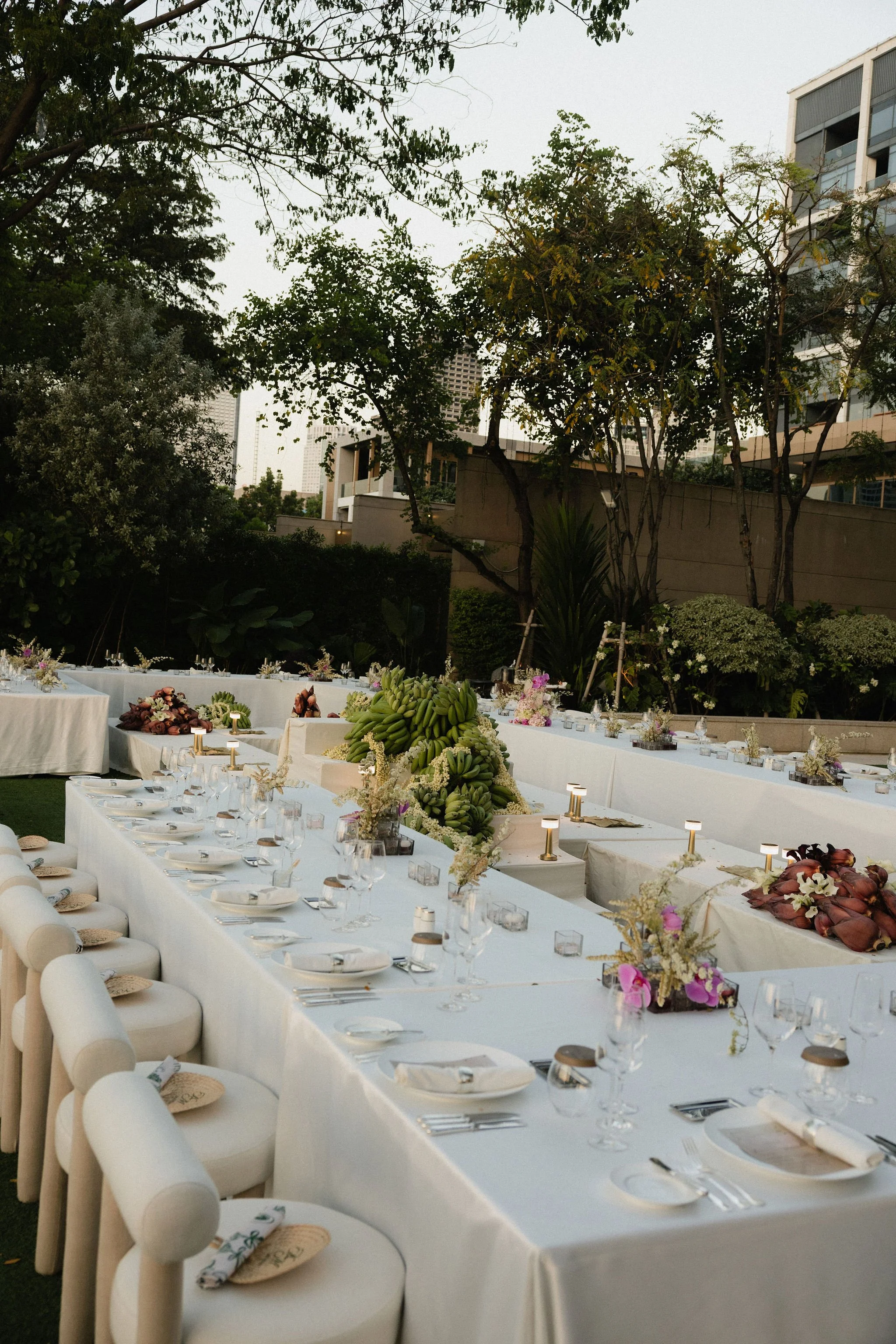 Outdoor wedding ceremony by the ocean with a bride and groom under a floral arch, surrounded by bridesmaids, groomsmen, and seated guests.