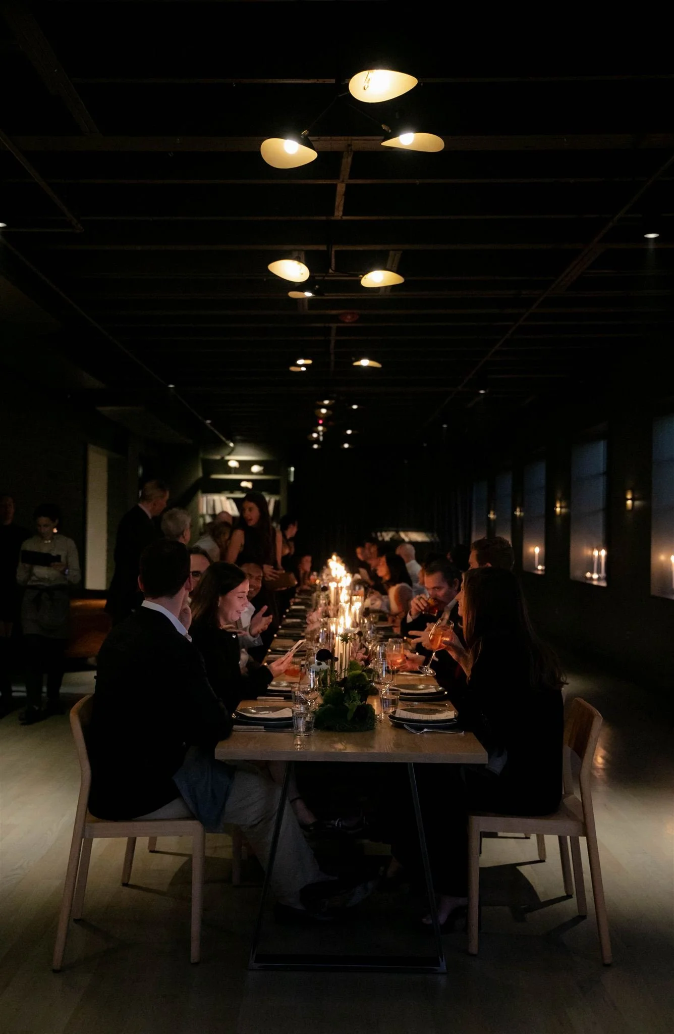 Wedding guests at a candlelit rehearsal dinner at Maxwells Trading Chicago wedding venue.