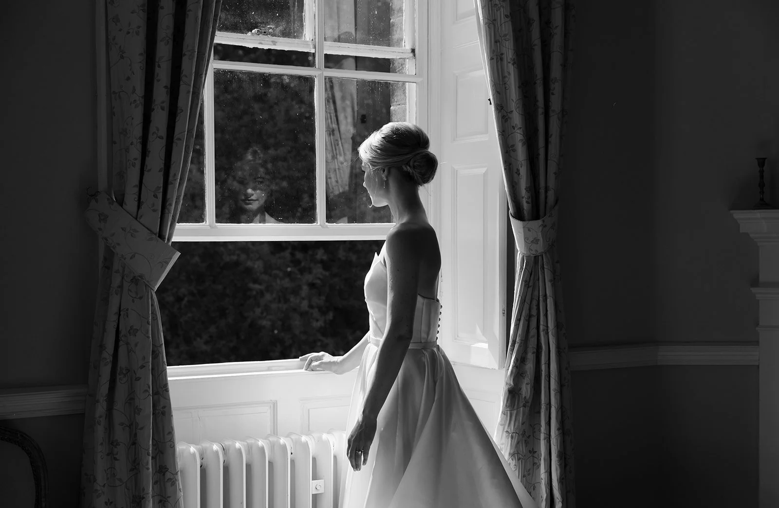 A bride looking out of the window at Middleton Lodge Estate on a wedding day in North Yorkshire.