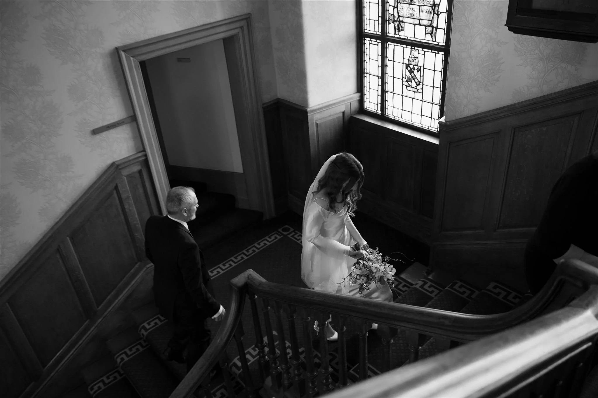 Bride and father walking upstairs in Edinburgh City Chambers on her wedding day in Edinburgh, Scotland.