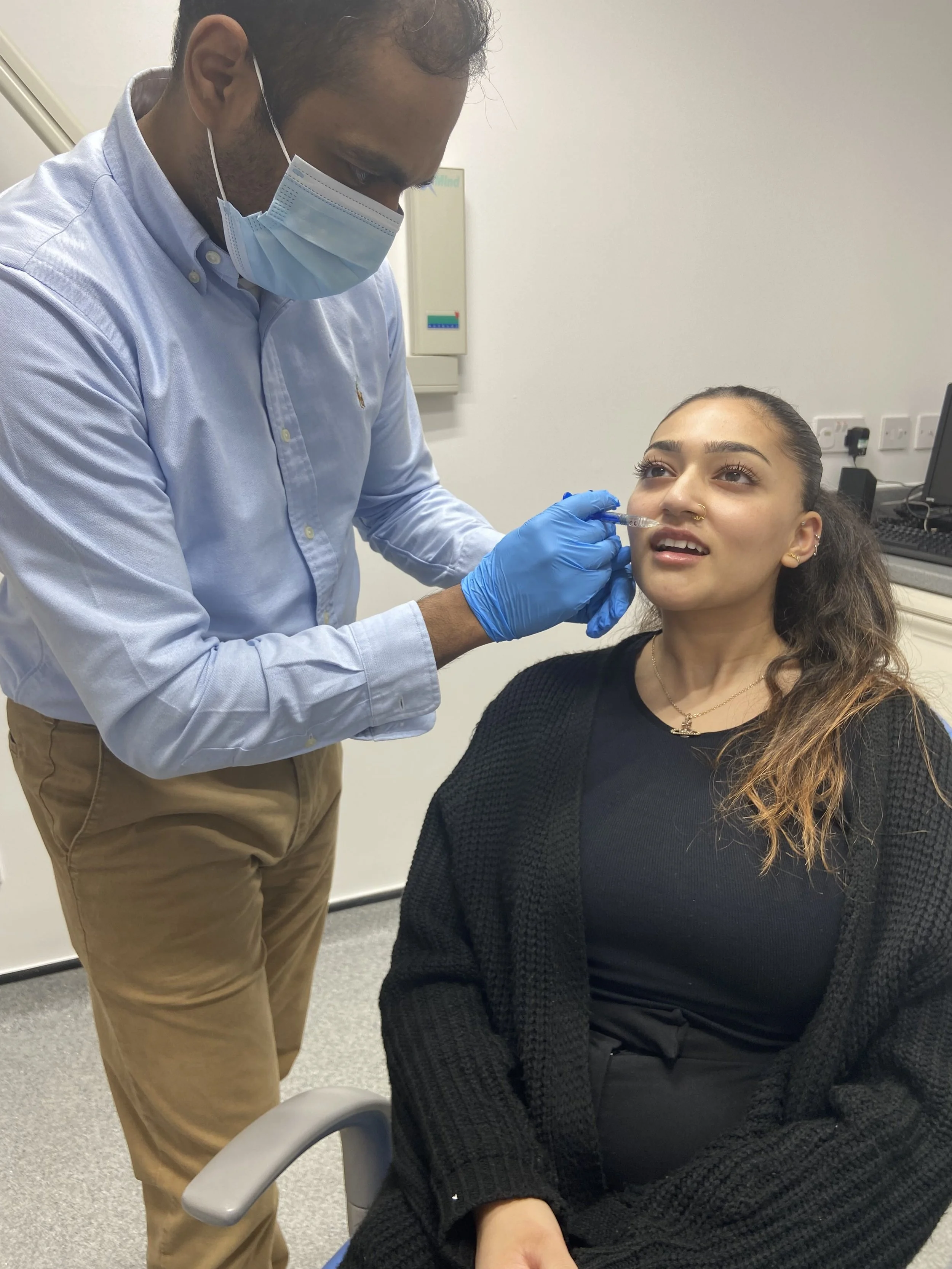 A healthcare professional administers a nasal spray vaccine to a woman in a clinical setting.