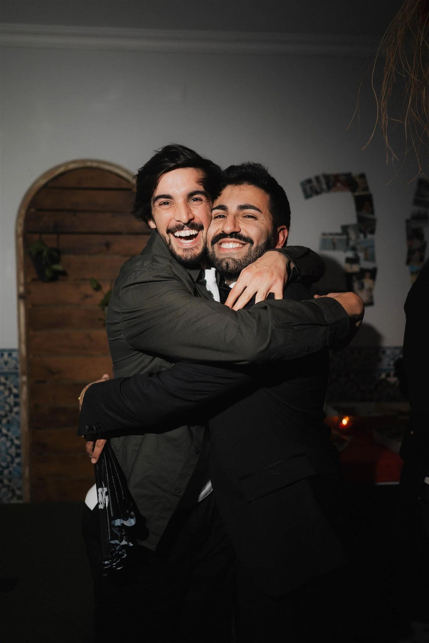 Two men hugging and smiling during a celebration or gathering indoors.