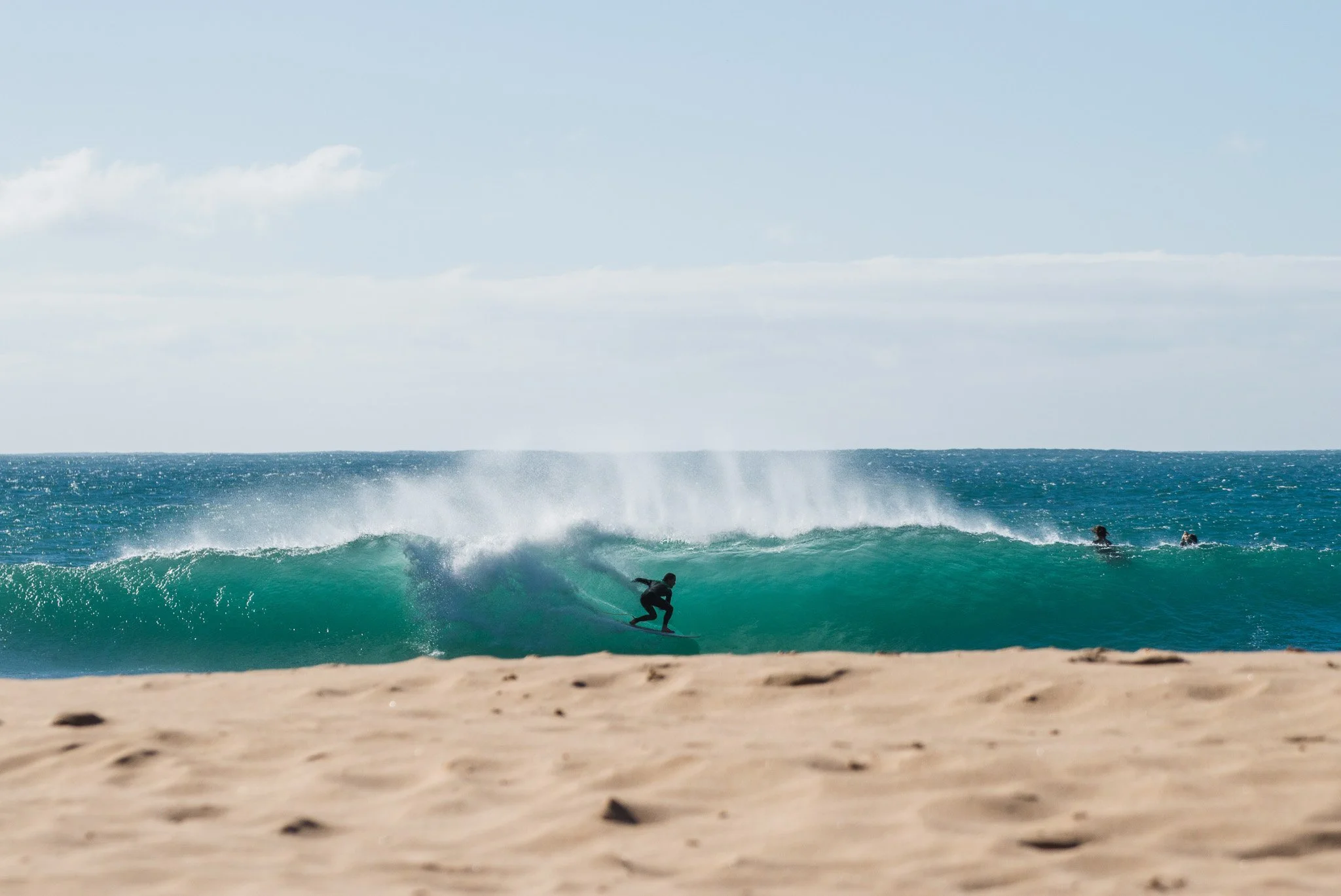 A surfer doing a barrel in a blue wave, in Algarve, Portugal