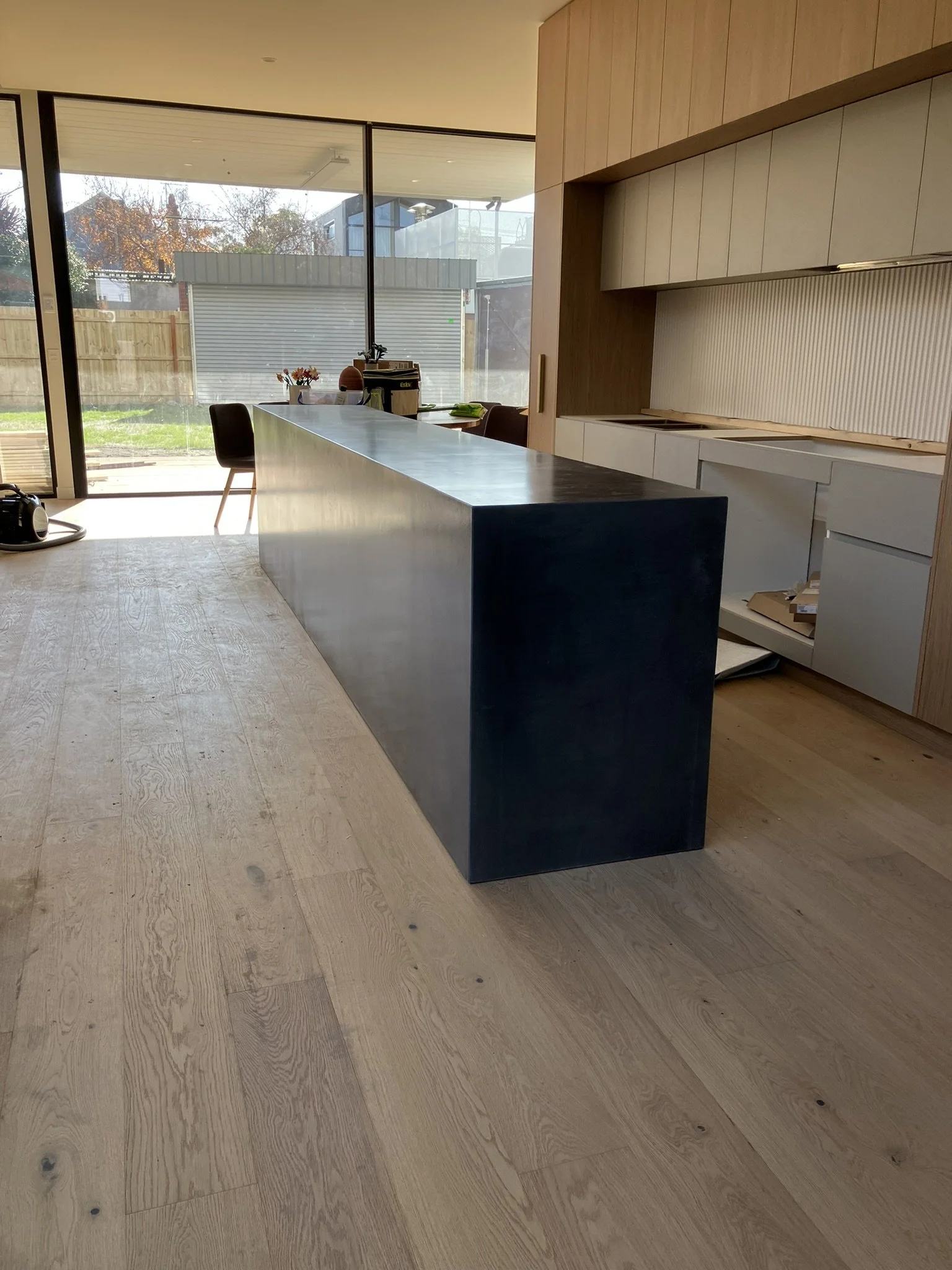 Custom concrete benchtop with bold waterfall edge and dark base cabinetry Melbourne