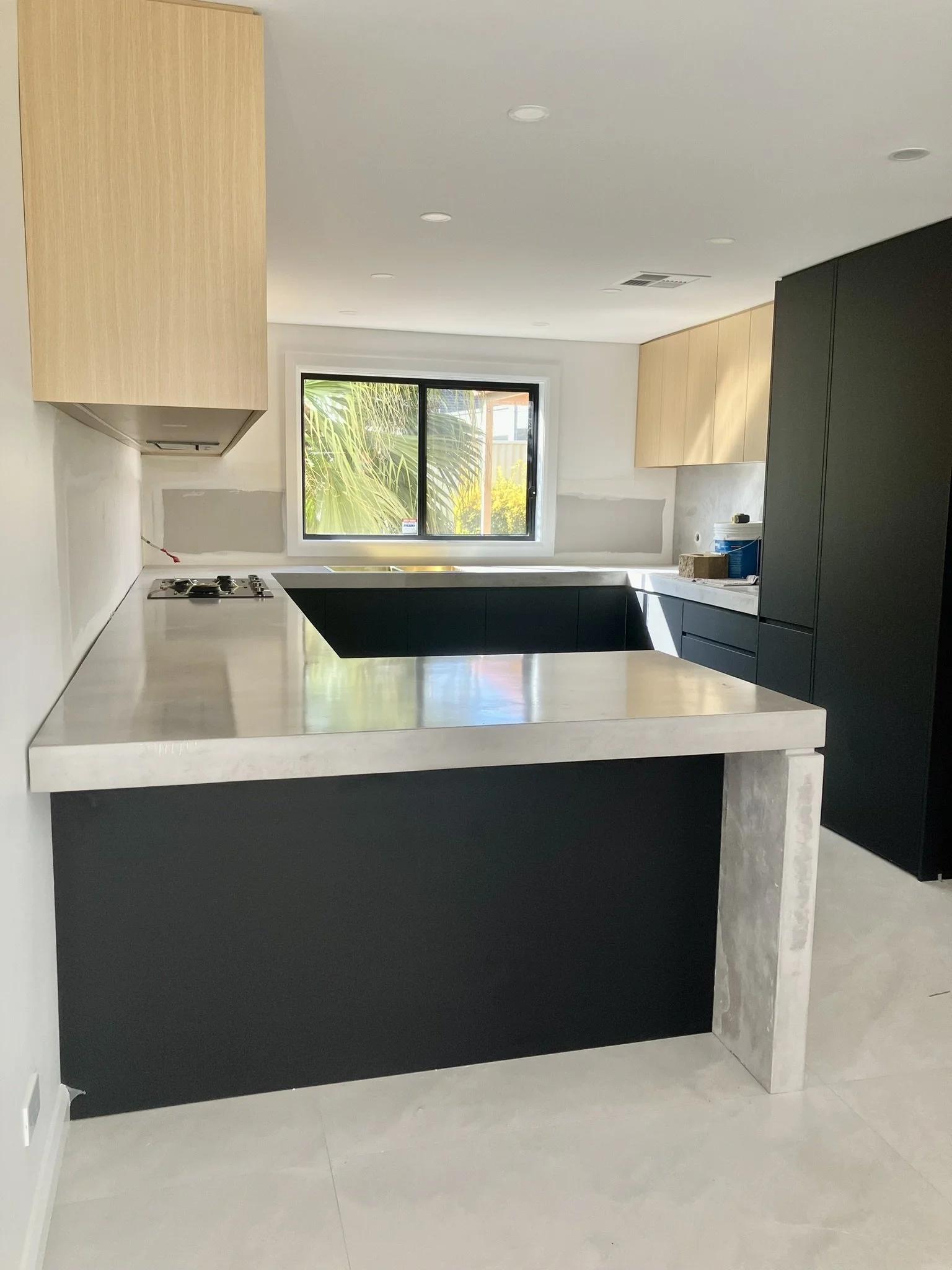 L-shaped concrete kitchen benchtop with waterfall edge and integrated cabinetry Melbourne