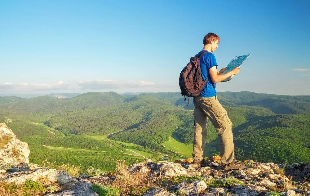 person on mountain top with a map guiding themselves