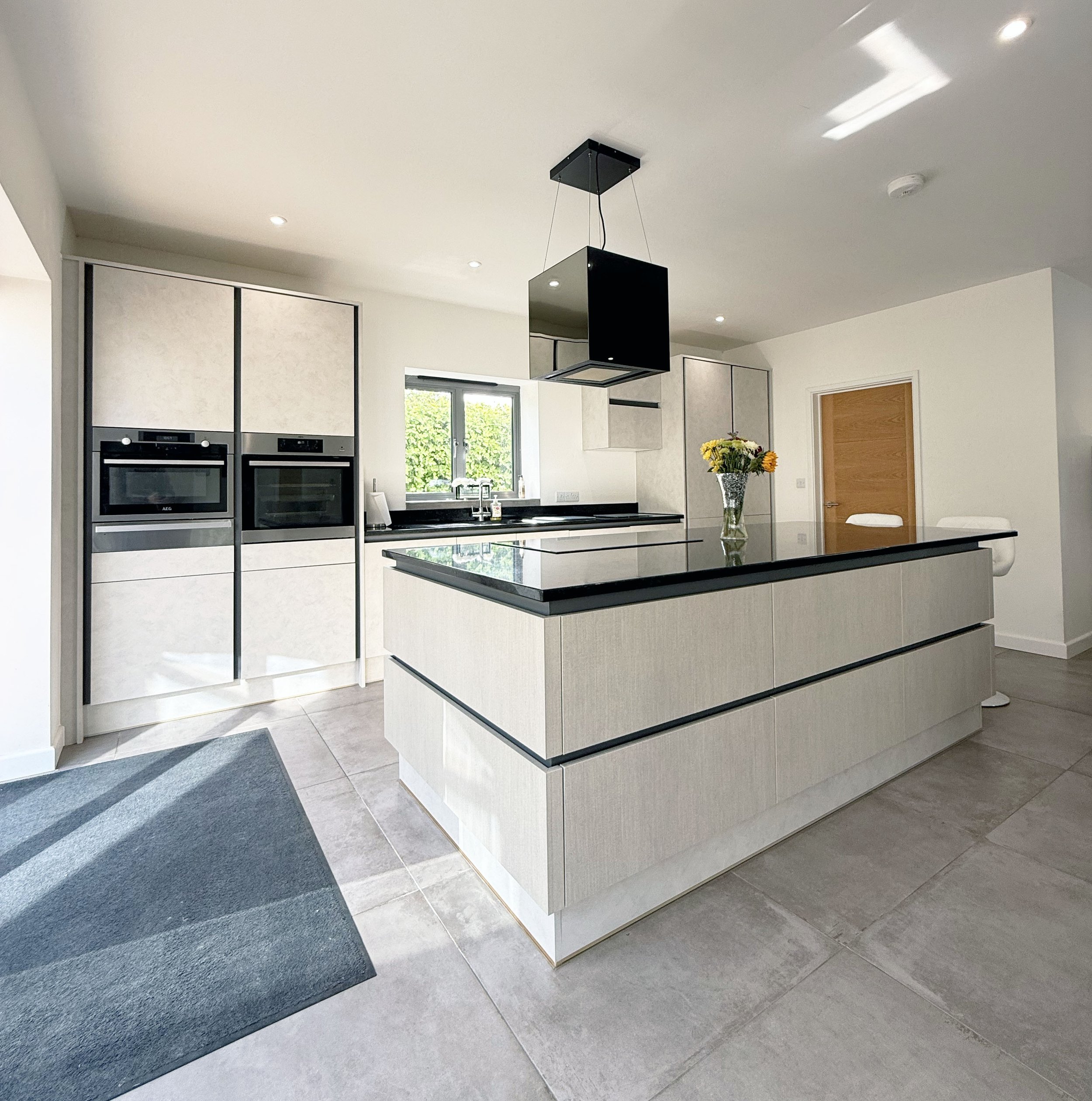 Modern kitchen with an island, built-in ovens, and a black countertop