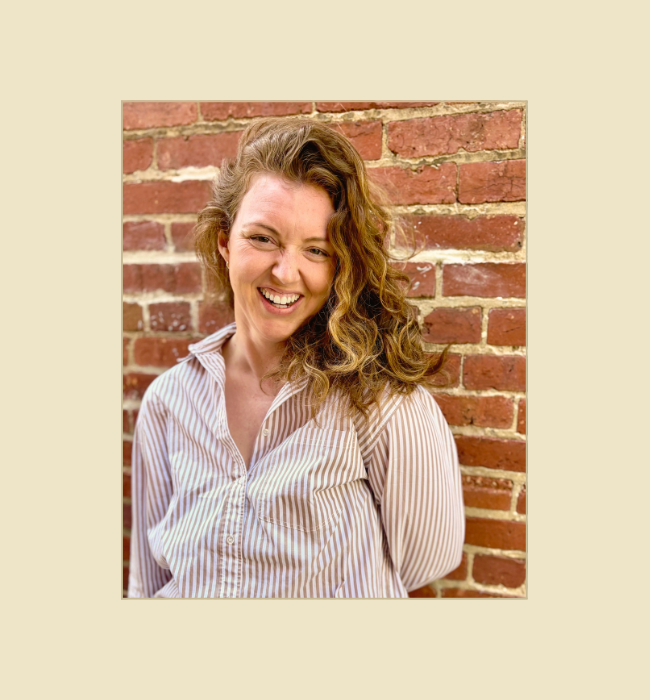 Kelsey Dunn, LMHC, somatic therapist in New York, standing against a brick wall.