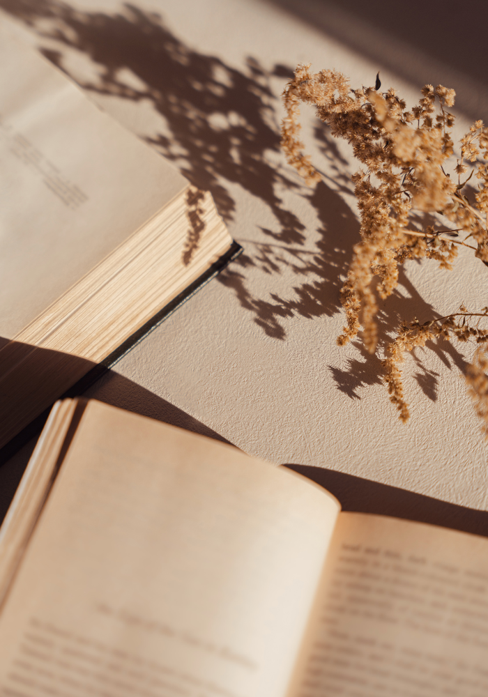Open books with dried golden flowers, representing recommended resources for women navigating anxiety in NYC.