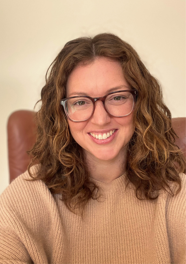 Kelsey Dunn, LMHC, somatic psychotherapist in New York City, seated in a warm neutral therapy space.