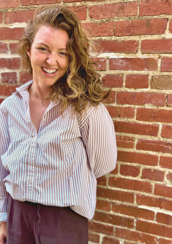 Kelsey Dunn, LMHC, who offers somatic therapy in NYC standing against a brick wall.