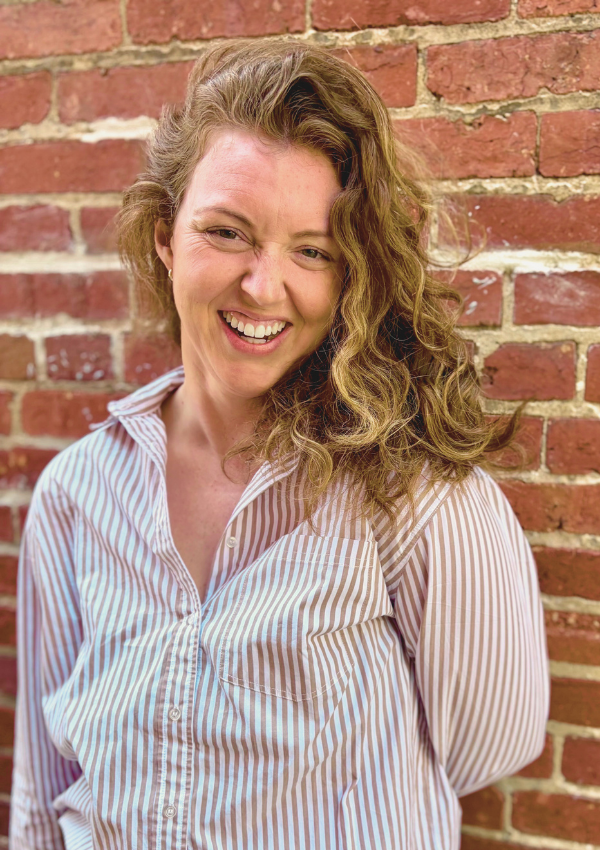 Kelsey Dunn, LMHC, who offers somatic therapy in NYC standing against a brick wall.