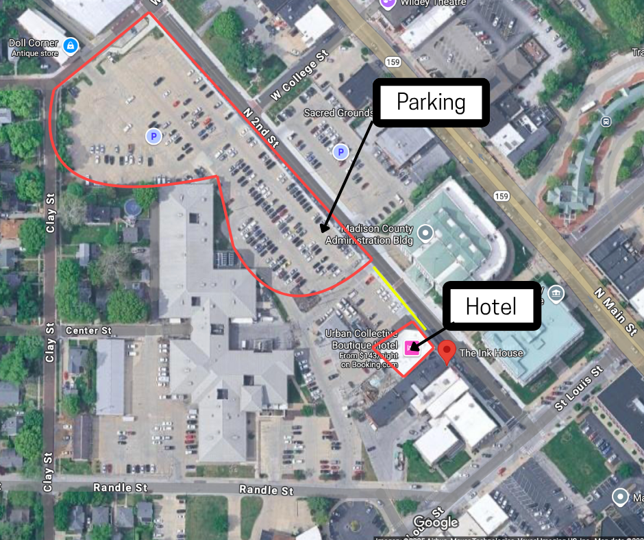 A map showing a parking lot, a hotel, and surrounding streets in an urban area. The parking lot is marked with a 'P' and outlined in red. The hotel is identified as 'Urban Collective Boutique Hotel' and 'The Ink House,' located near the parking lot on N Main Street. Directions are indicated from the hotel to the parking lot with arrows; the route is highlighted in yellow.