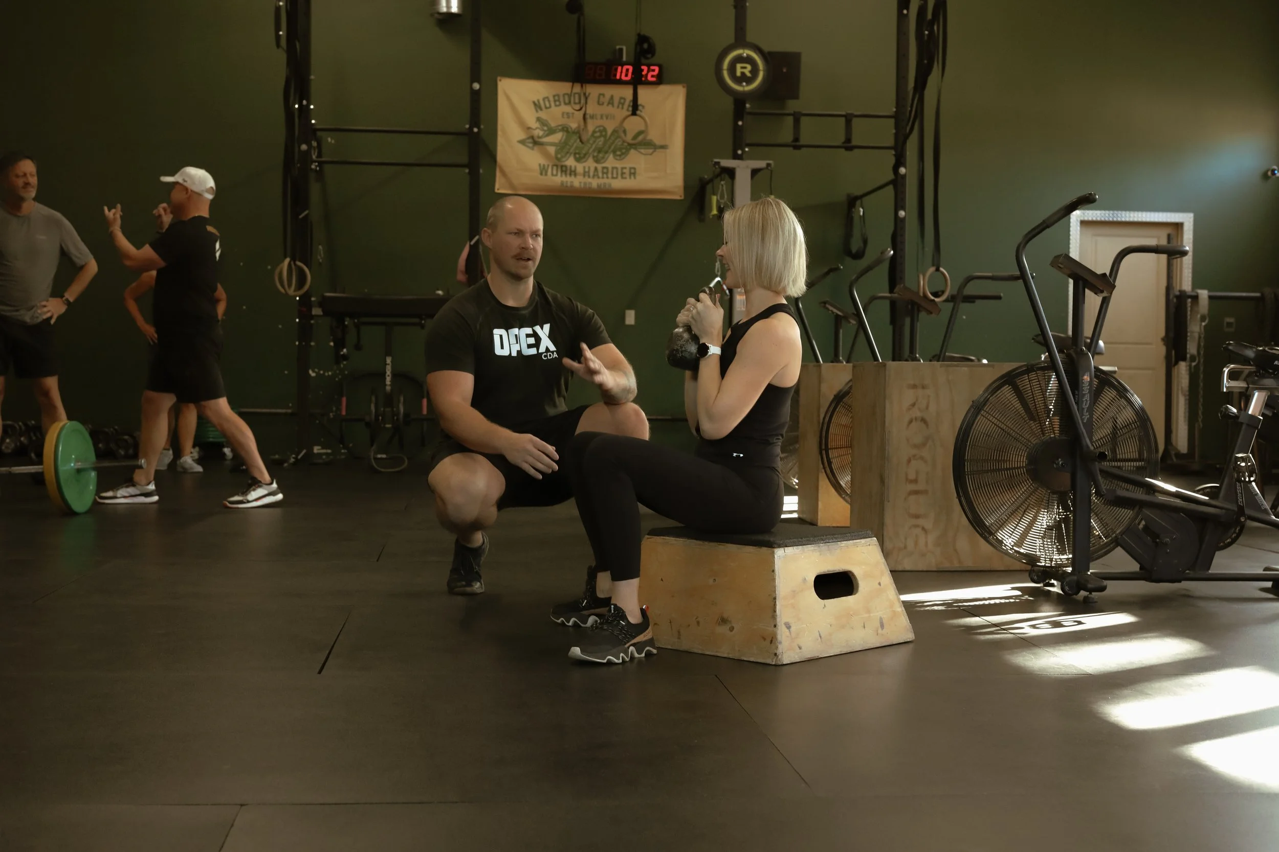 OPEX CDA coach providing individualized guidance to a member during her workout
