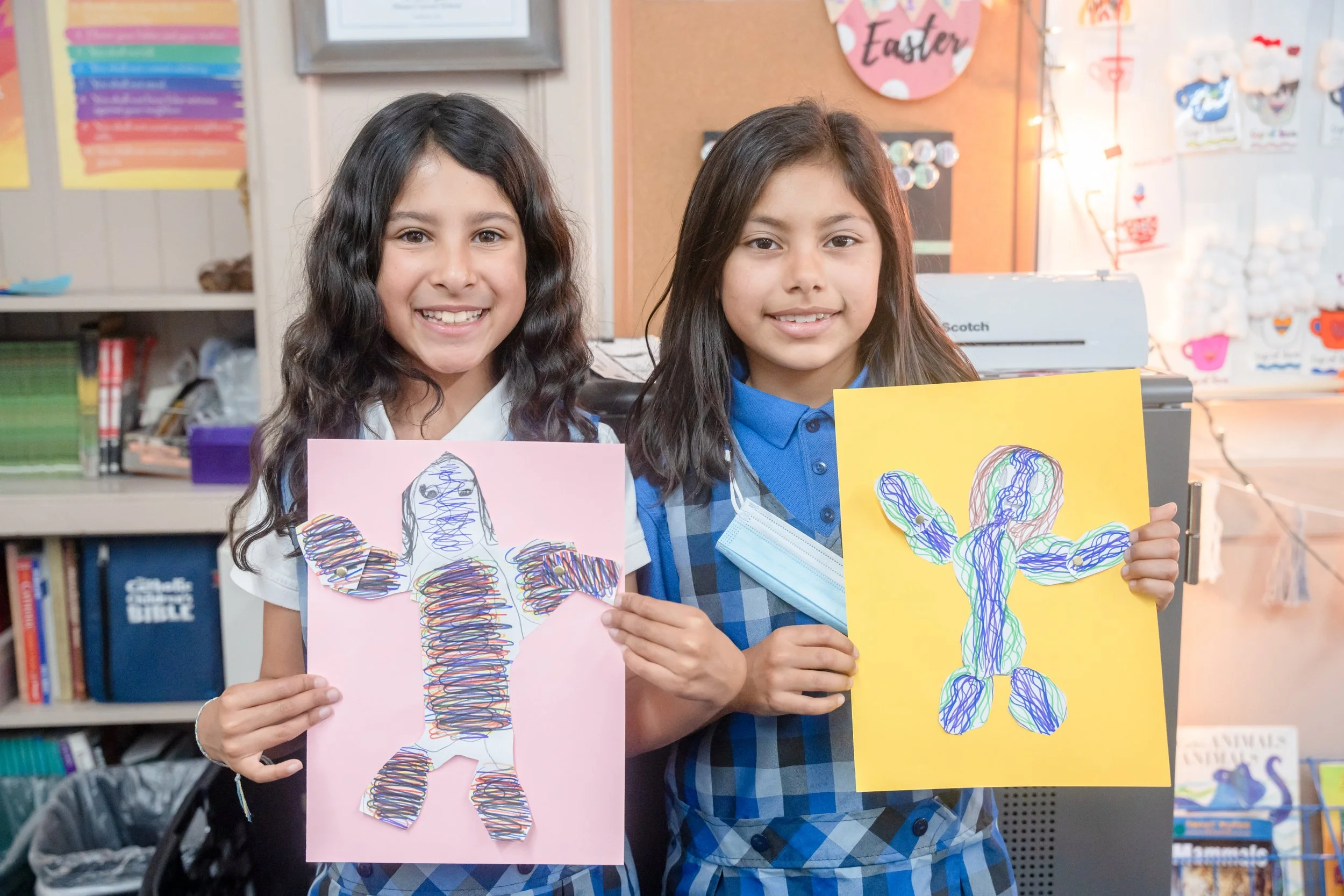 two students smiling and holding artwork