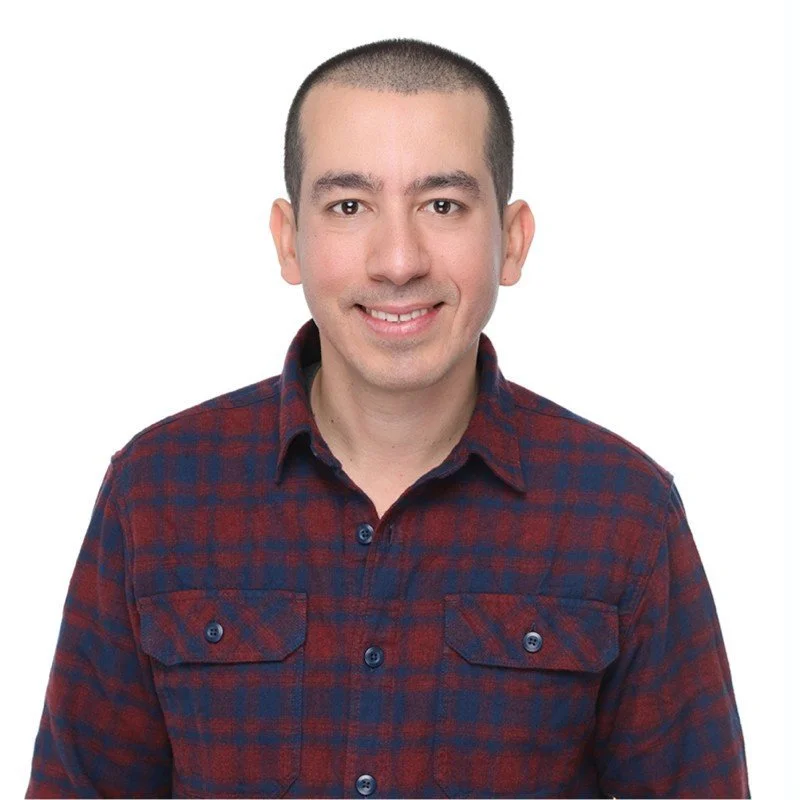 Ali Irturk headshot in a plaid button-up smiling