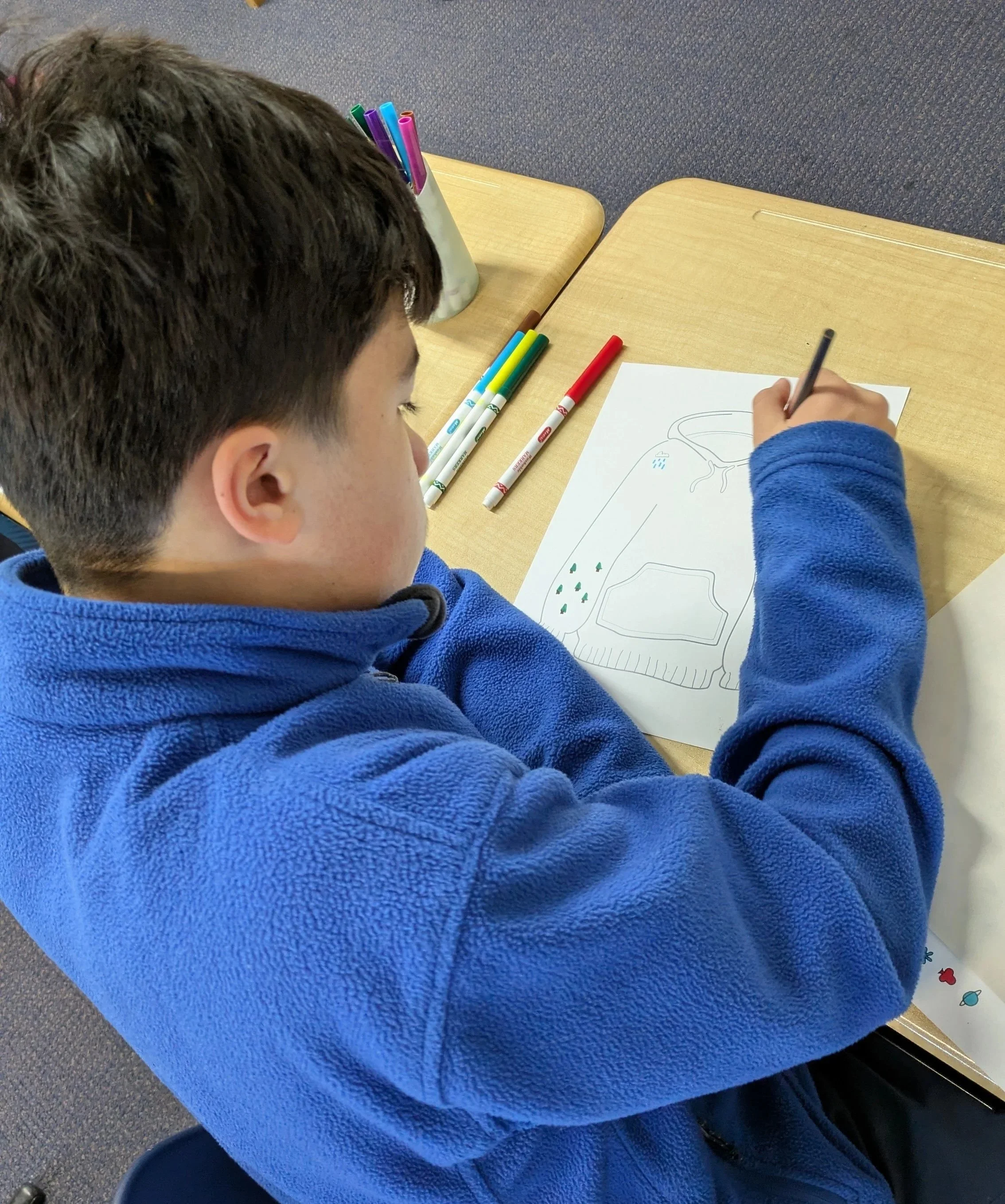 boy drawing the bliue sweater he is wearing