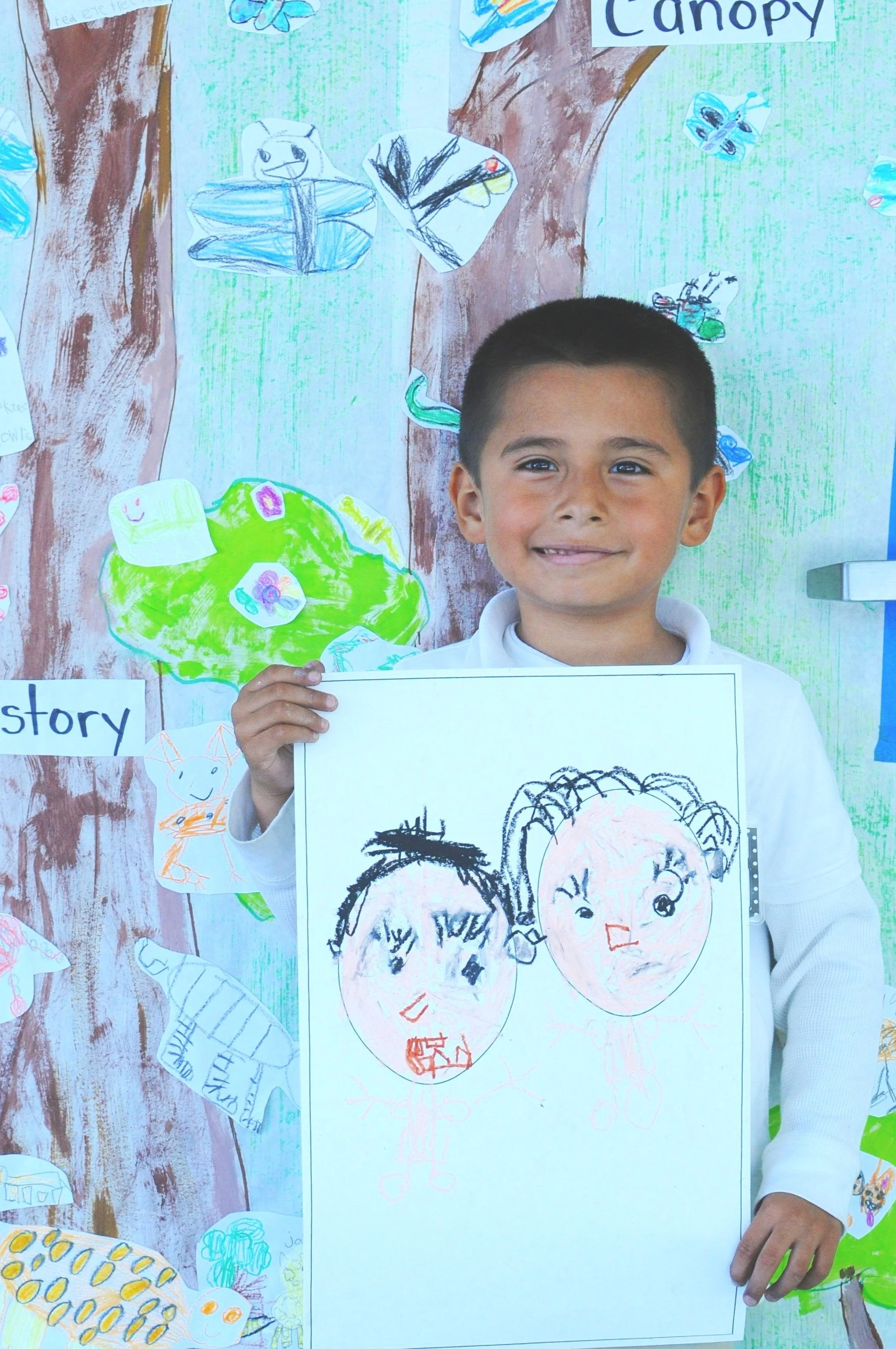 boy student smiling while holding his art