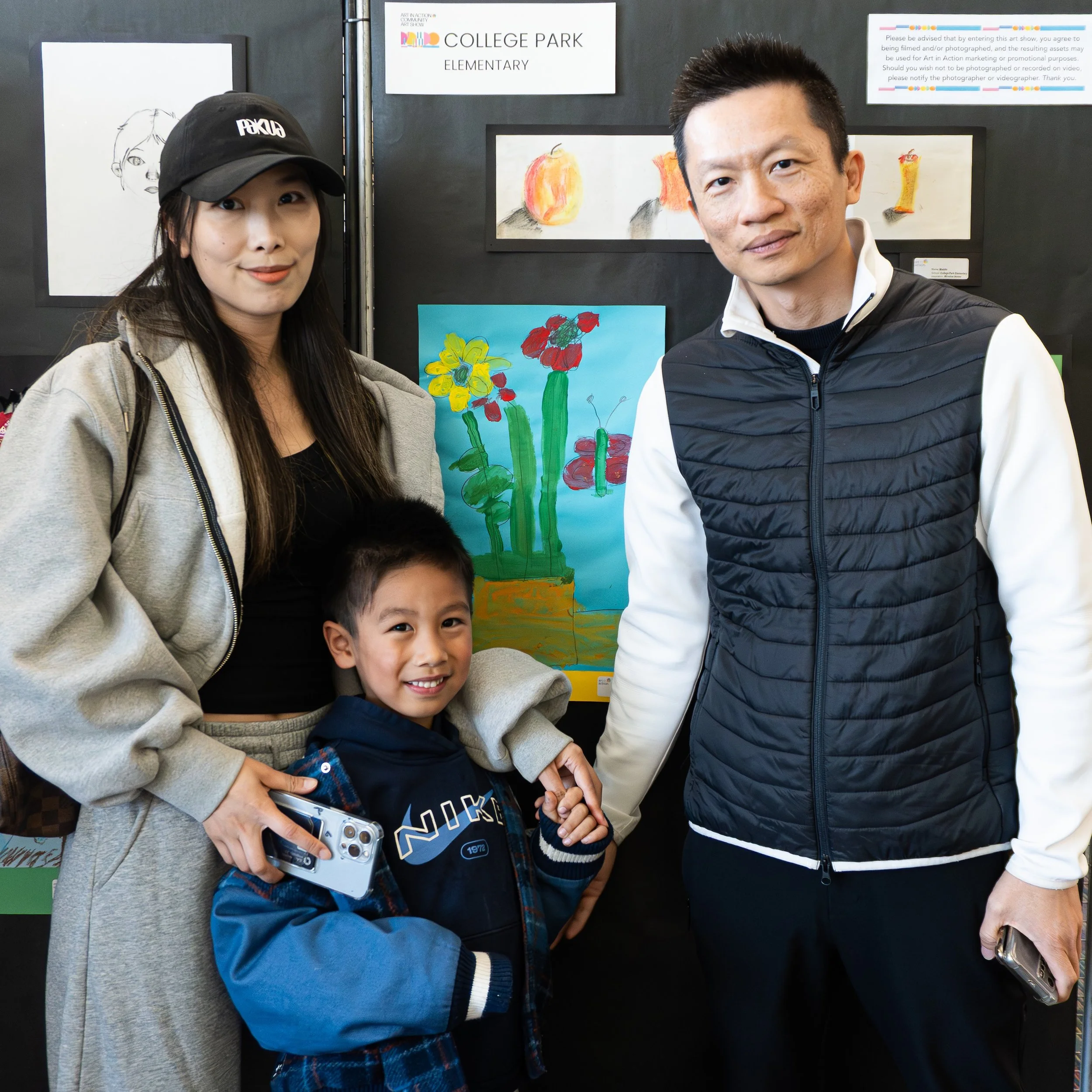 family posing in front of student art