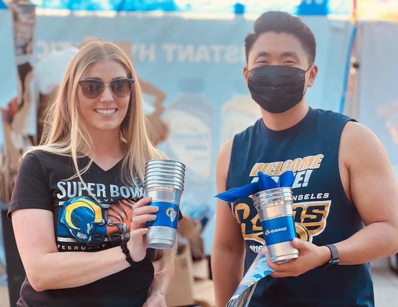 Super Bowl and Los Angeles Rams brand ambassadors holding branded promotional cups at an outdoor event - Event Staffing Live